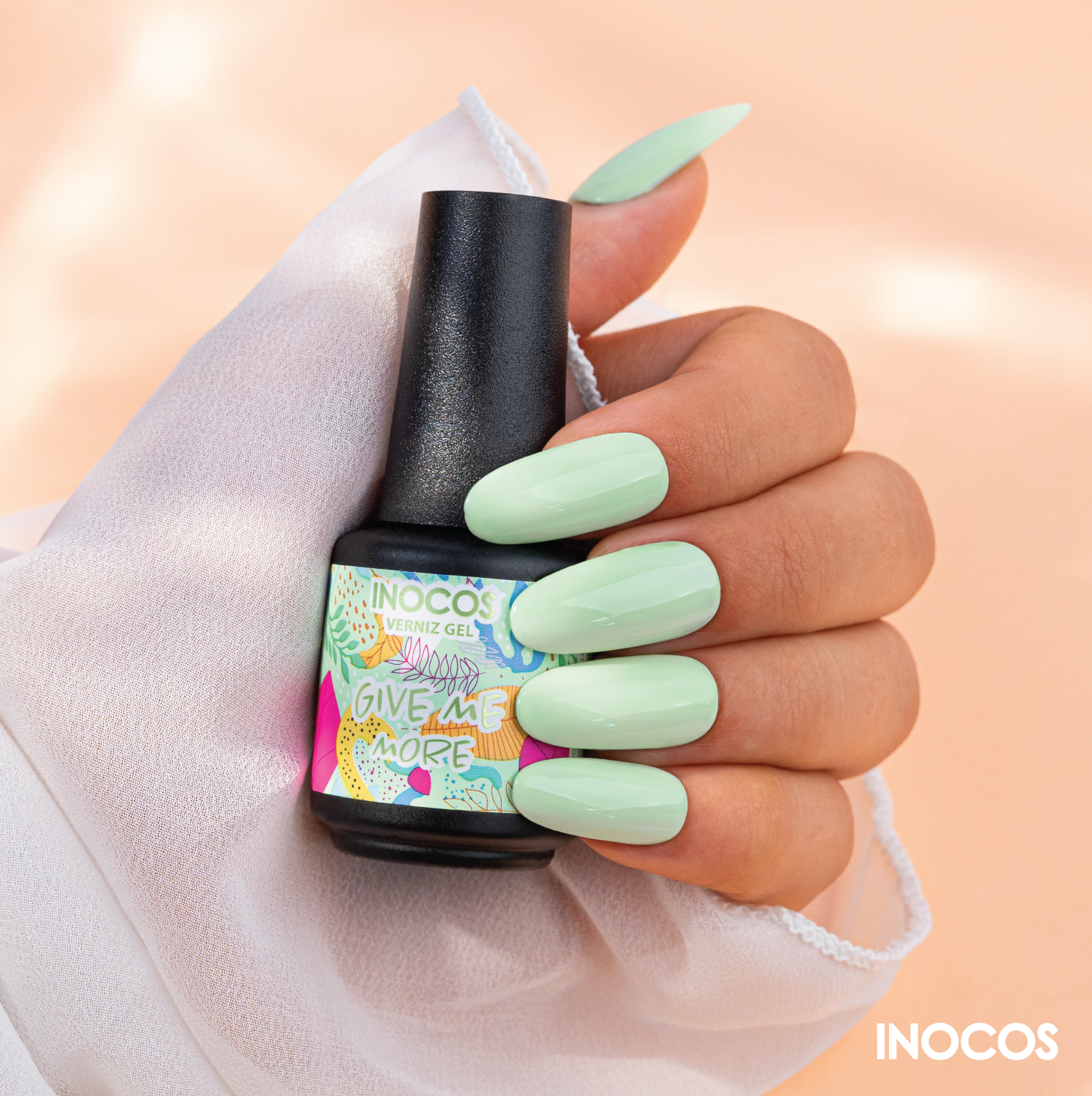 Frasco de verniz gel INOCOS verde pastel com mão feminina a segurar