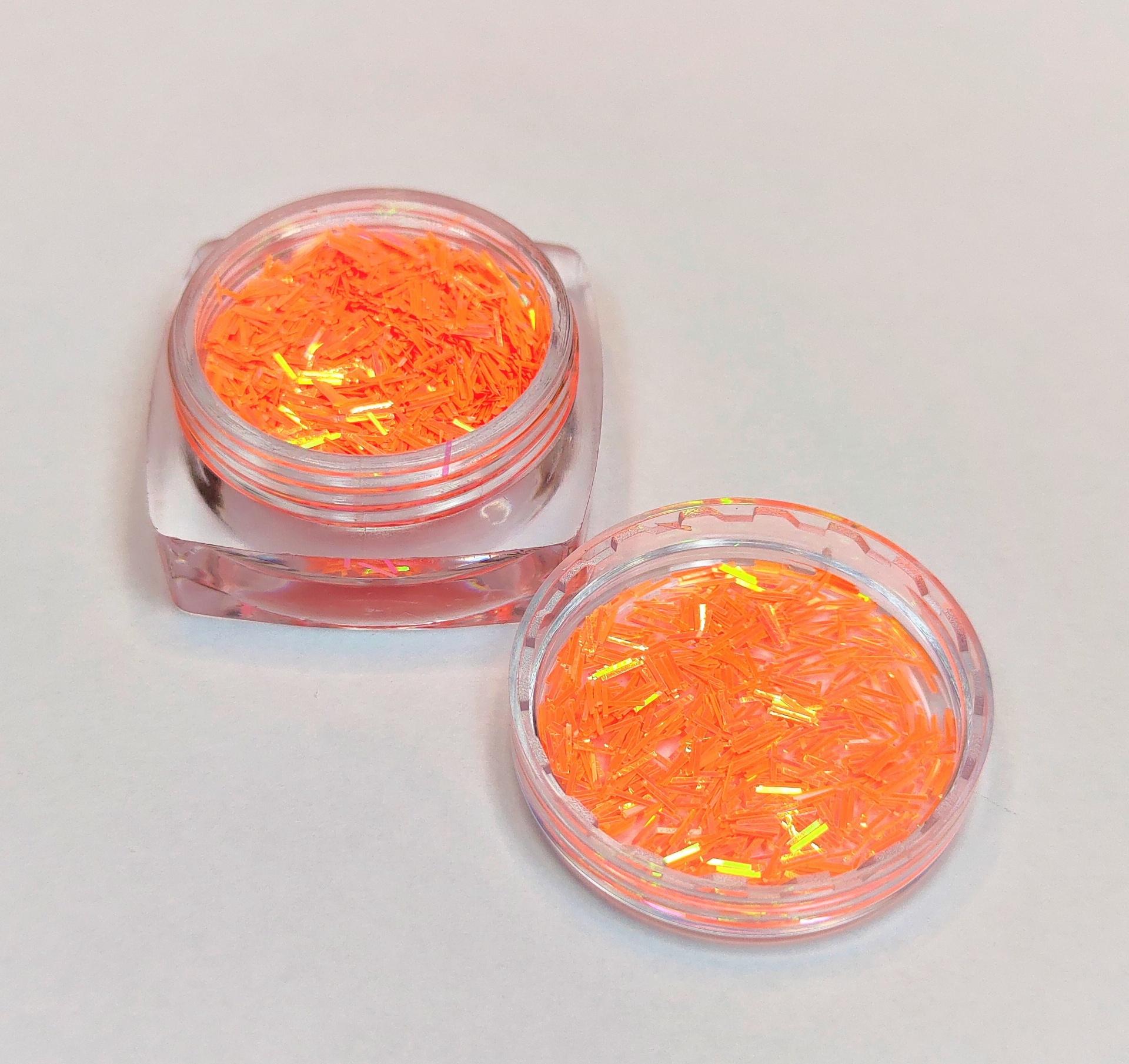 Dois frascos transparentes com glitter laranja iridescente