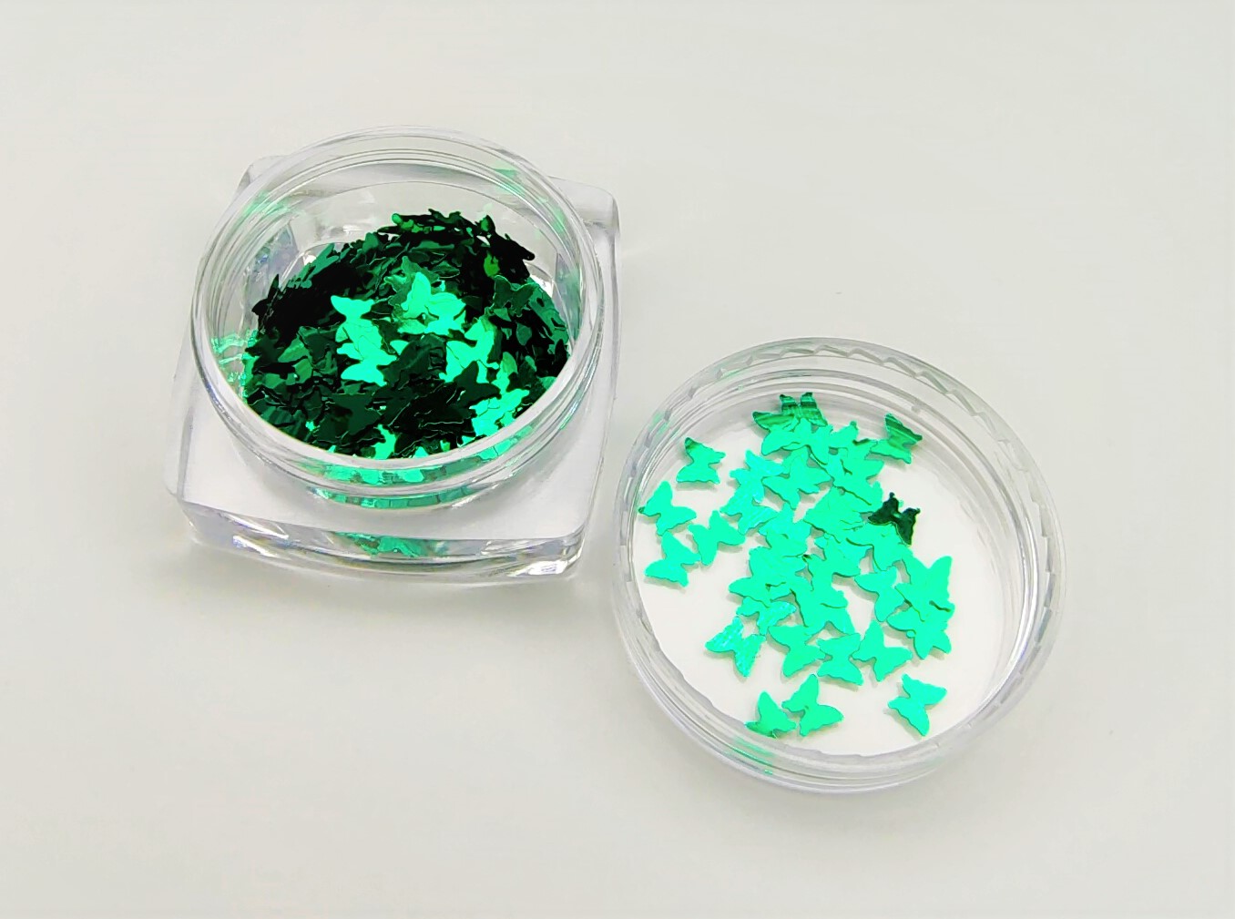 Recipientes com purpurinas em forma de borboletas verdes.