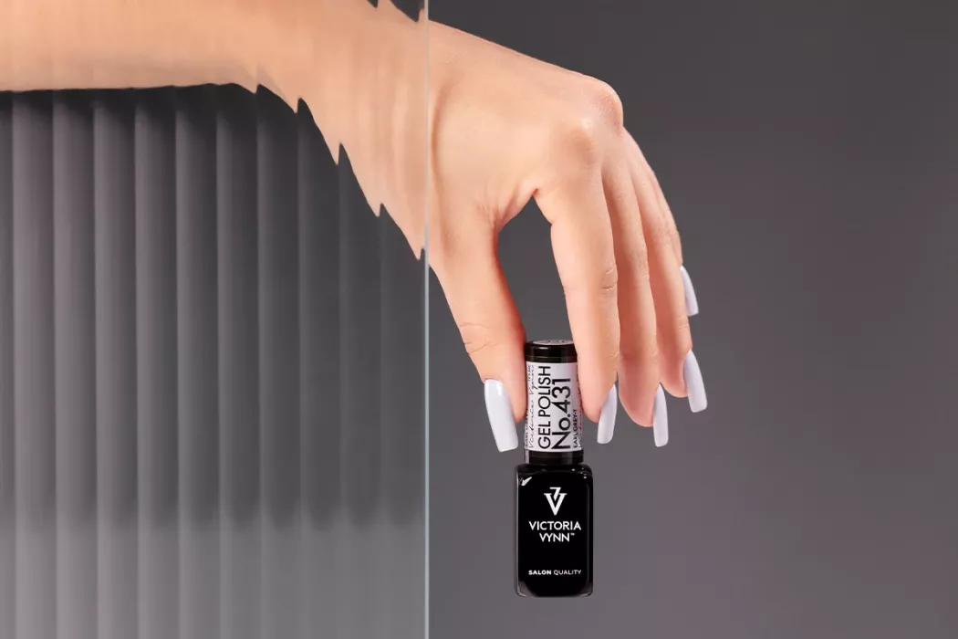 Mão com verniz gel cinza claro segurando frasco de Victoria Vynn