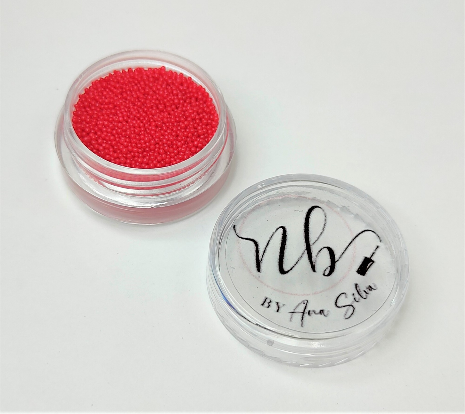 Pote transparente com esferas vermelhas e tampa com texto NB BY Ana Silva