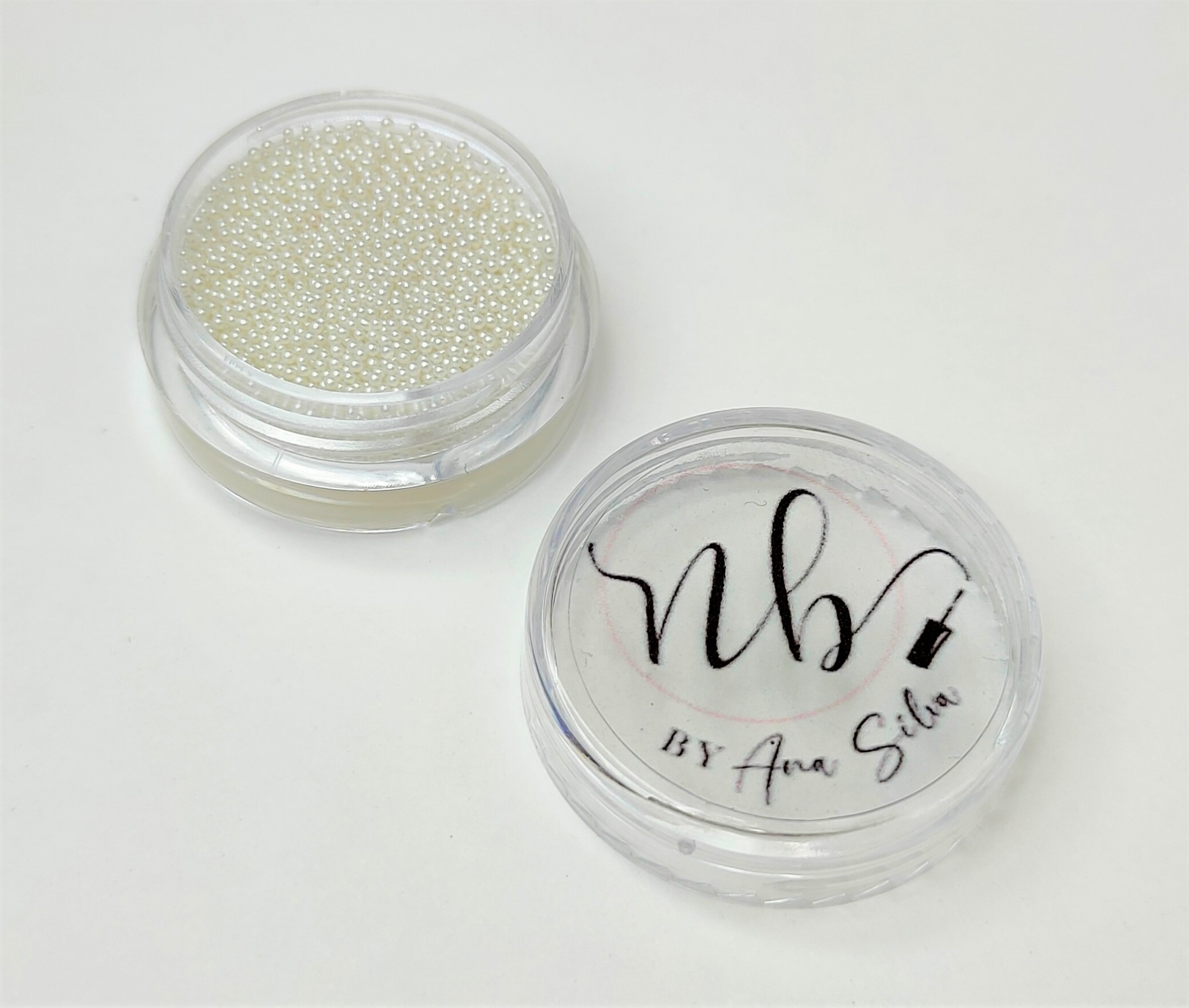Frasco redondo transparente com pérolas brancas e tampa com escrita NB BY Ana Silva