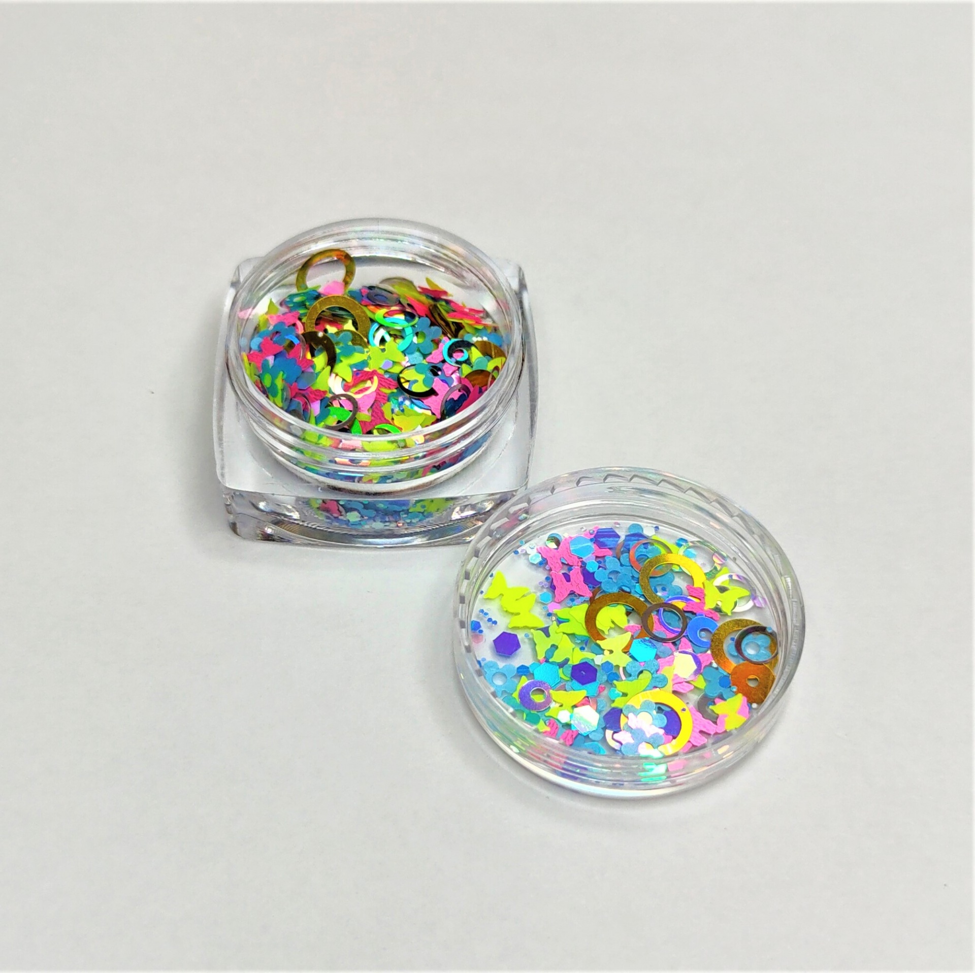 Caixas transparentes com lantejoulas coloridas em superfície branca