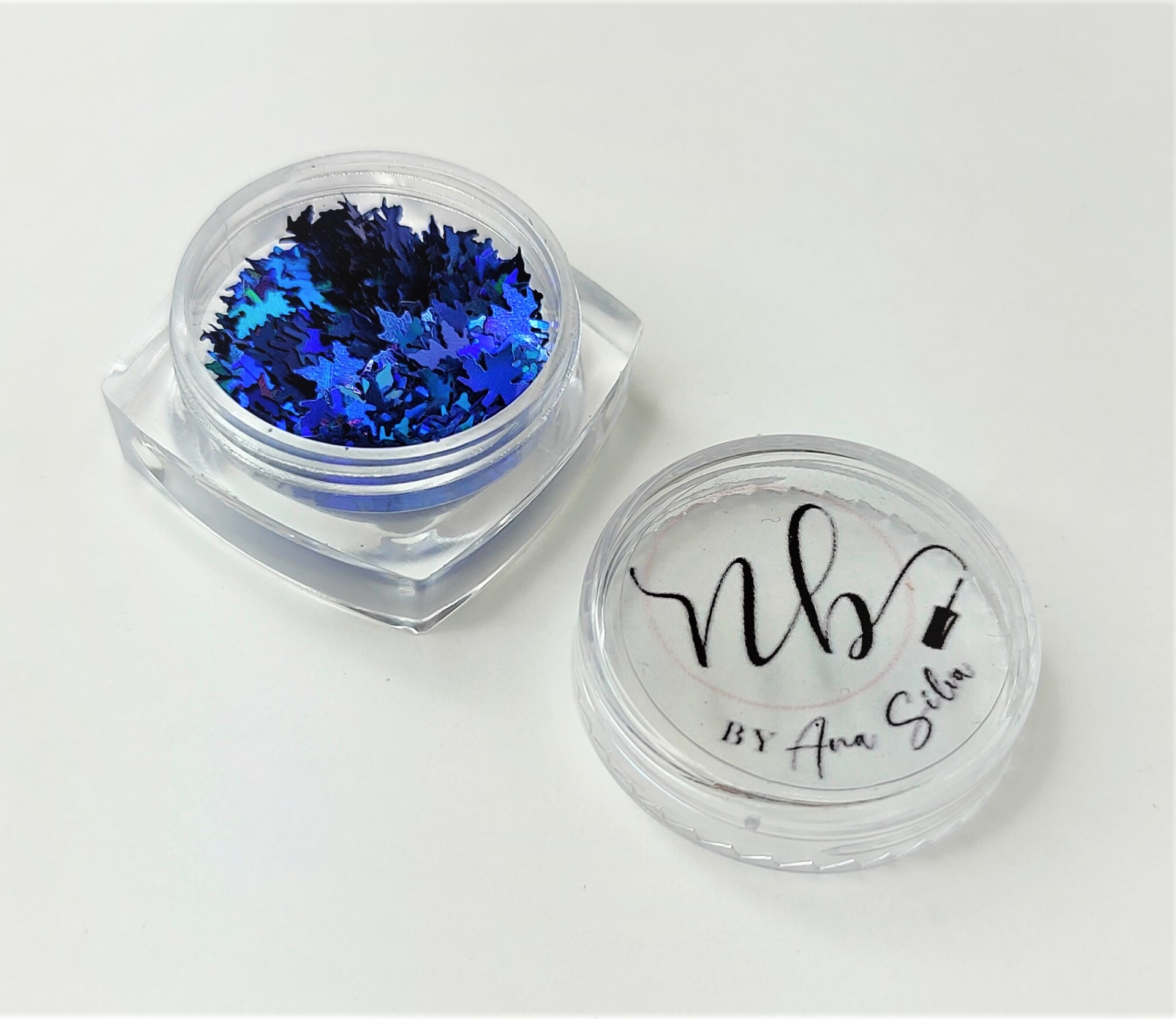 Pote de plástico transparente com lantejoulas azuis em forma de estrelas e tampa com texto VB BY Ana Silva.