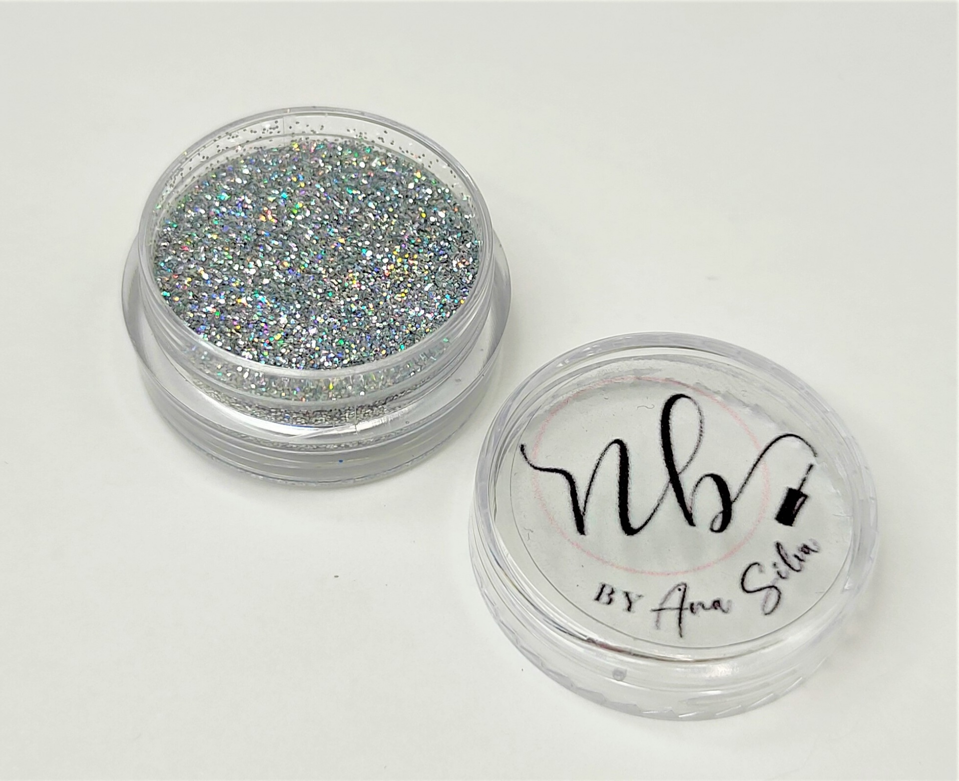 Pote de glitter holográfico prateado transparente com tampa com texto NB BY Ana Silva