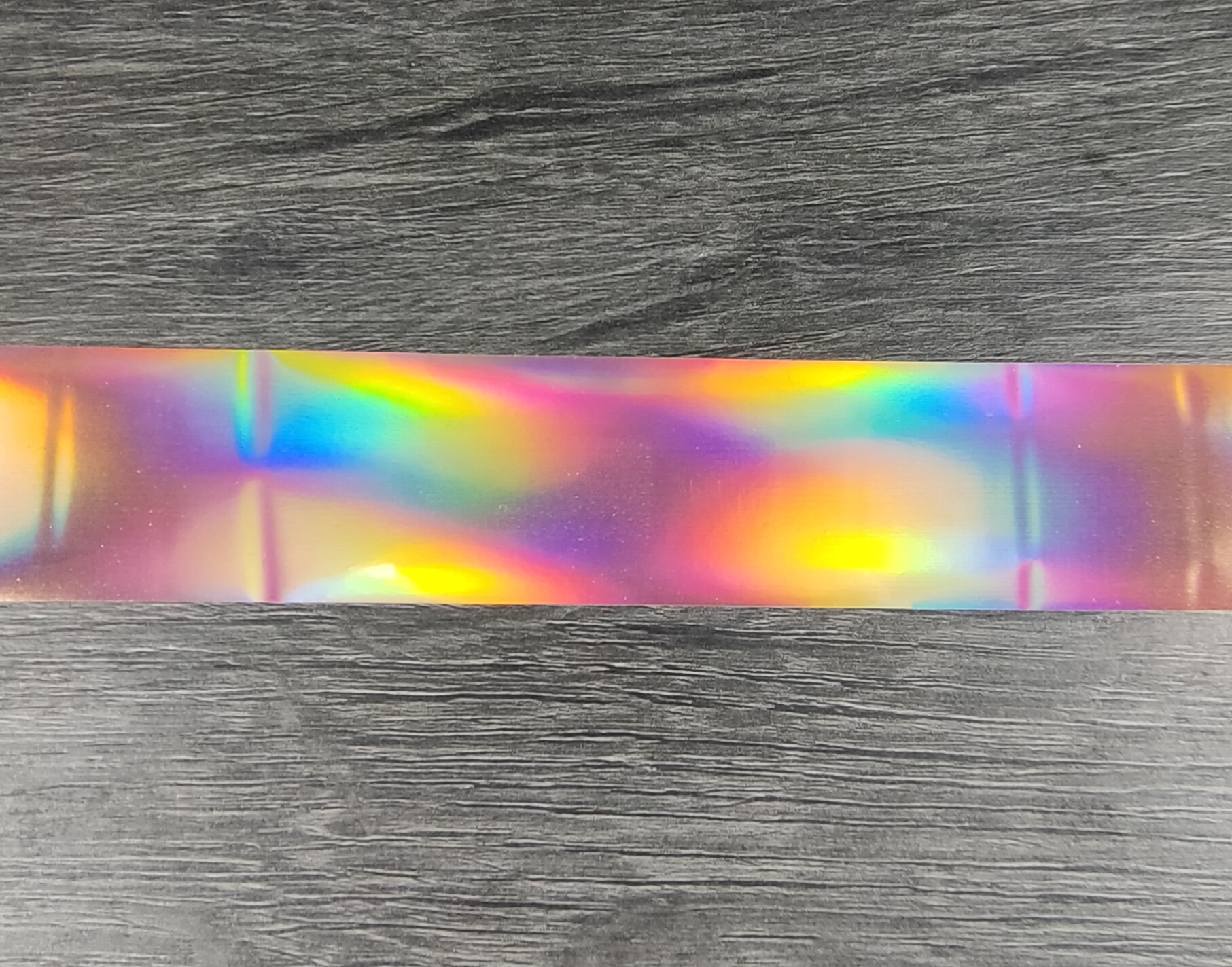 Fita iridescente colorida sobre mesa de madeira cinzenta
