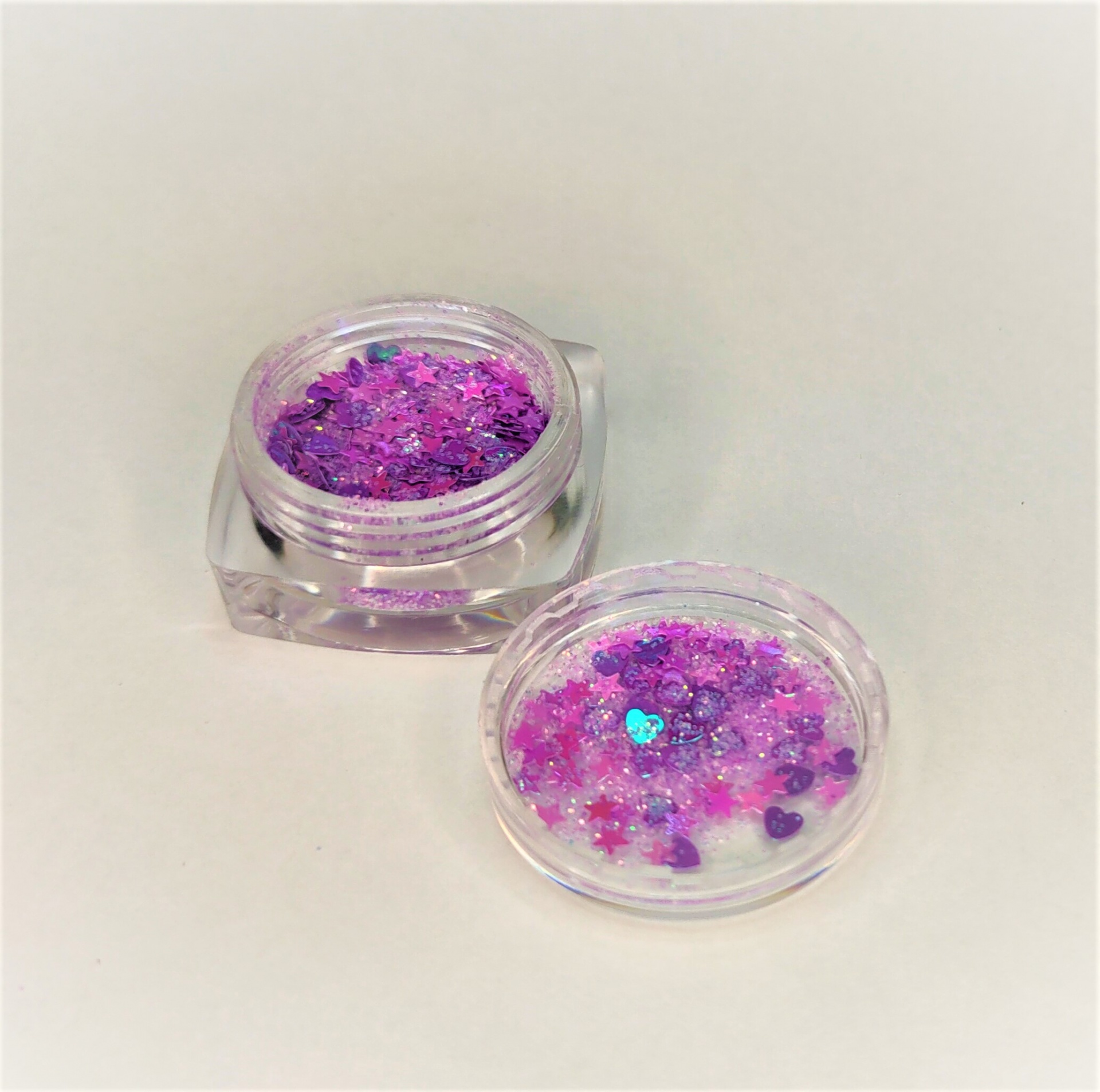pote transparente com glitter rosa e roxo em forma de corações