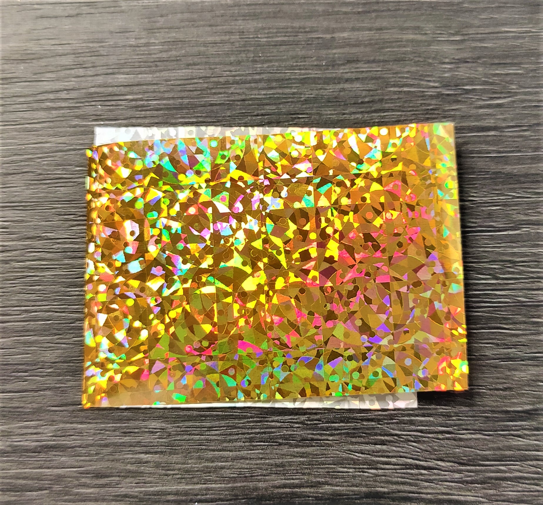Cartolina holográfica dourada sobre superfície de madeira escura