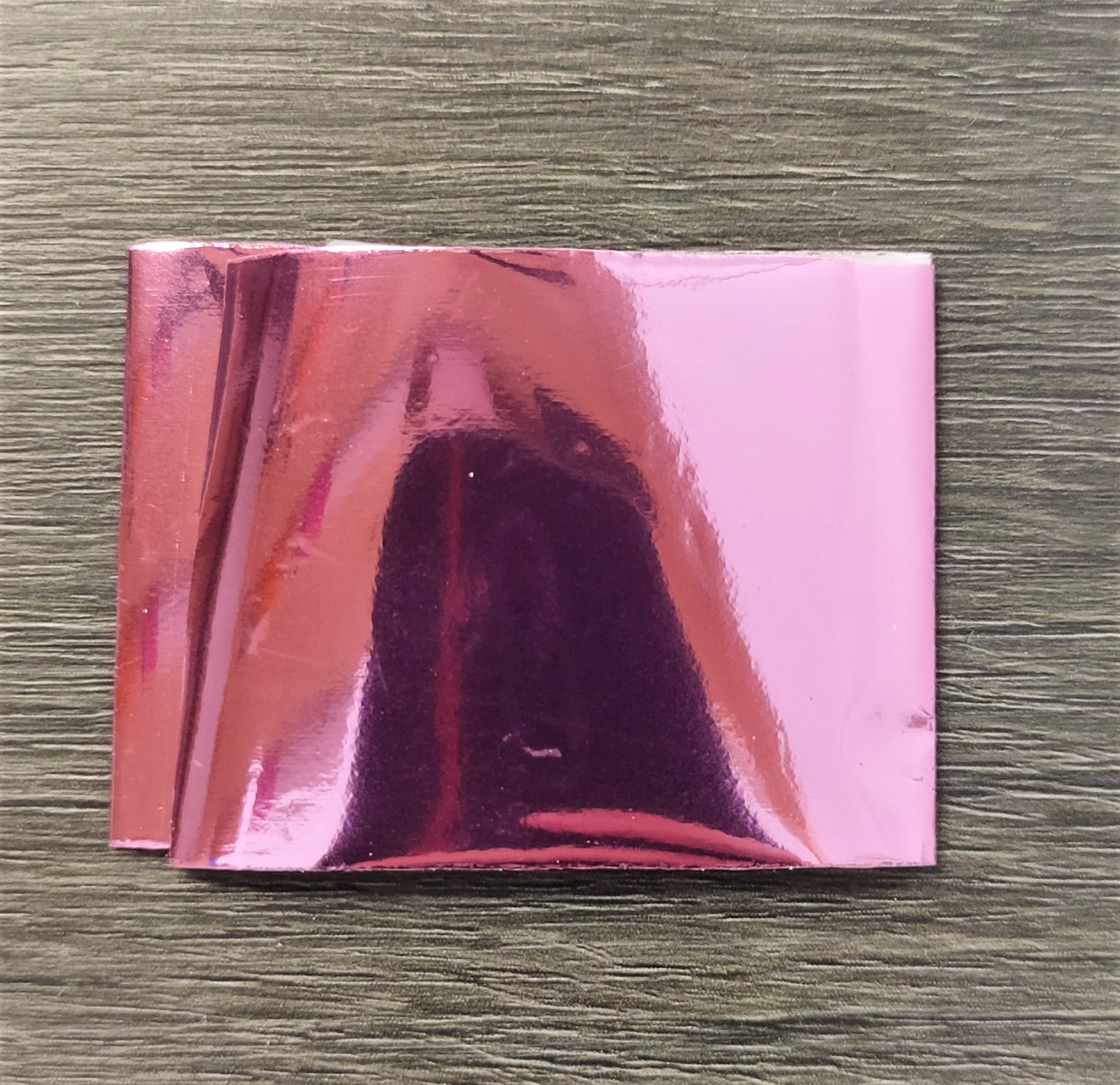 Folha metálica rosa brilhante sobre madeira