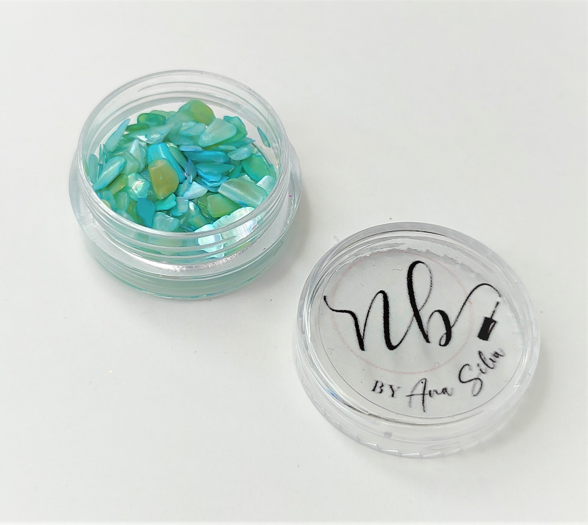 Embalagem transparente com peças decorativas turquesa e verde e tampa com texto NB BY Ana Sita
