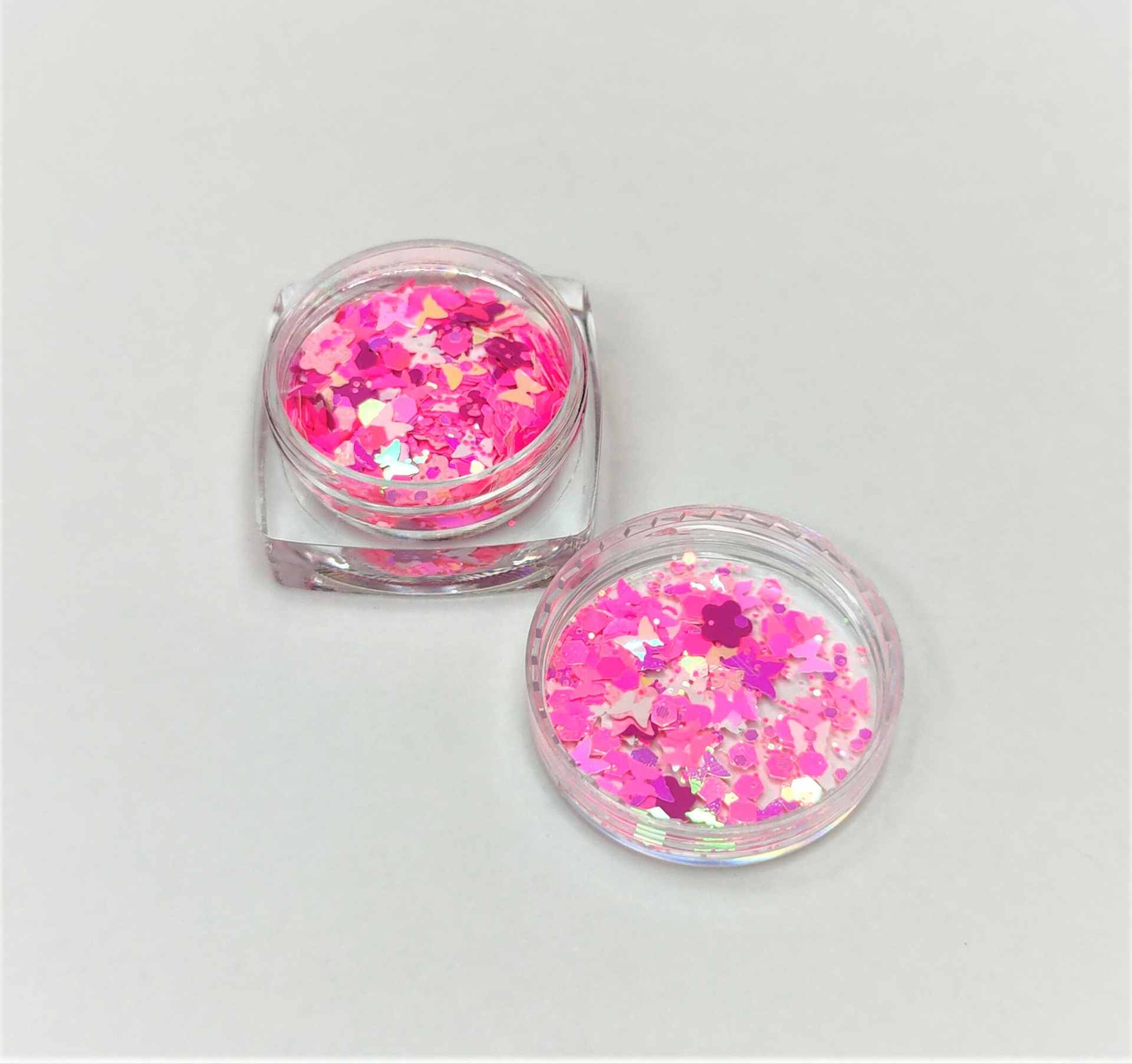 Pote transparente pequeno com glitter rosa e branco e tampa ao lado