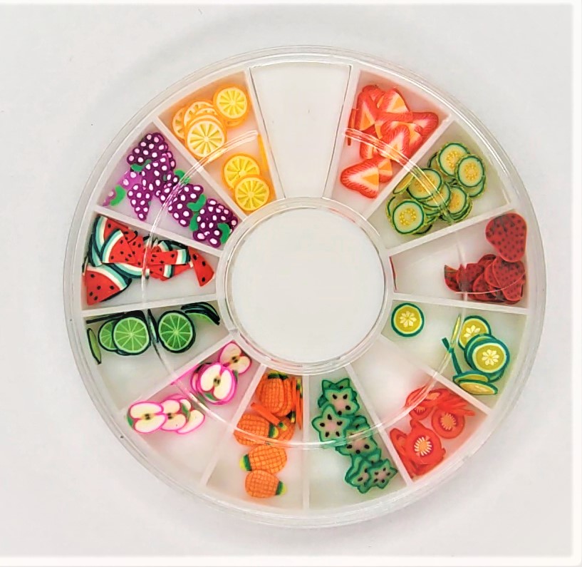 Caixa redonda com divisórias contendo enfeites em polímero coloridos em forma de fatias de frutas e legumes.