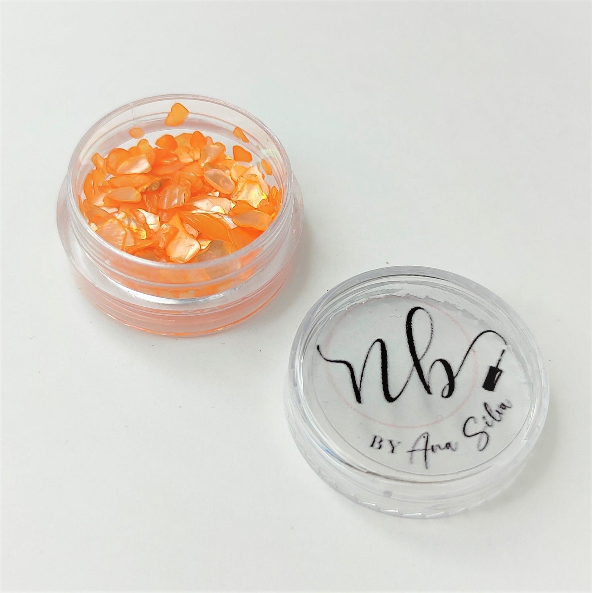 Recipiente transparente com pedaços laranja e tampa com texto Nb BY Ana Silva