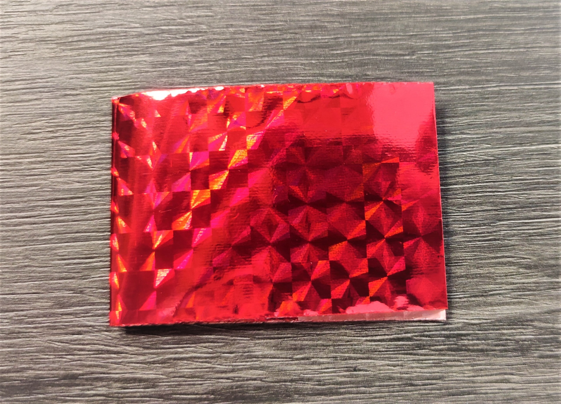 amostra holográfica vermelha brilhante sobre mesa de madeira cinzenta