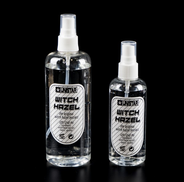 Duas garrafas transparentes de spray com extrato de hamamélis, rótulos brancos e pretos, em fundo preto