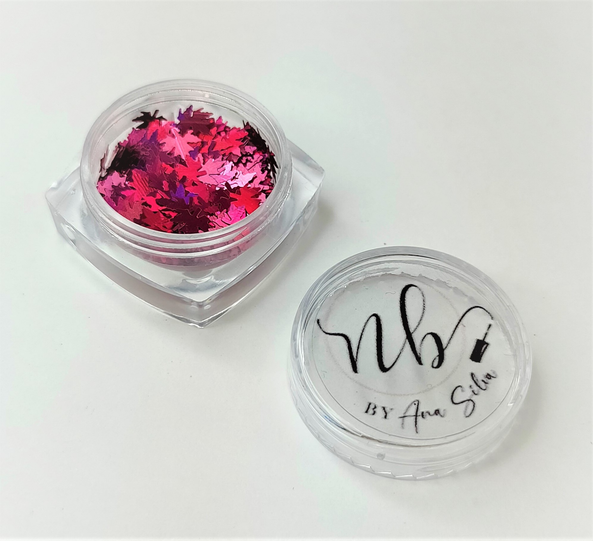 Frasco pequeno de plástico com glitter rosa e tampa com texto 'nb BY Ana Sita'