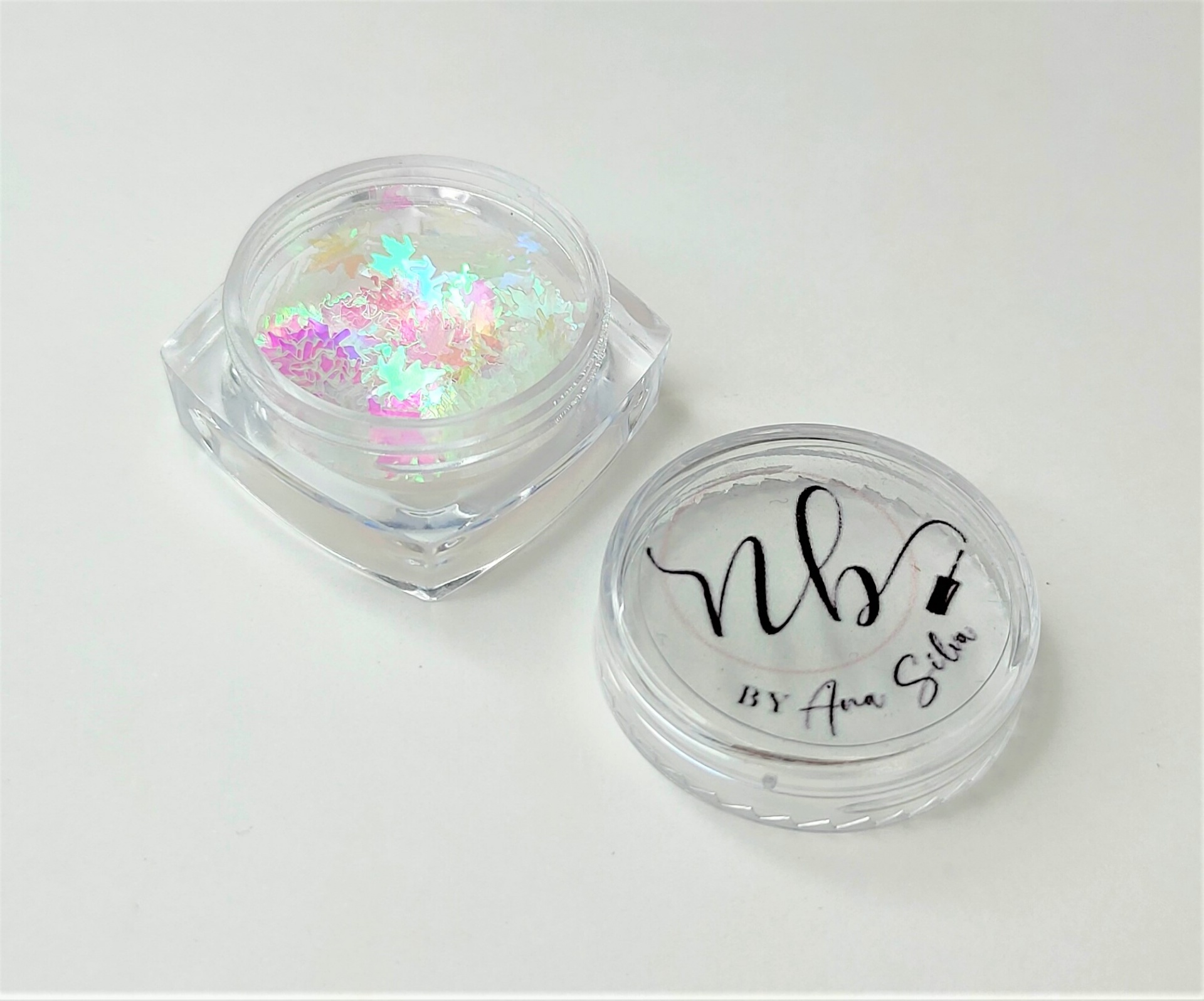 Pote transparente de glitter com tampa removida e texto 'NB BY Ana Santos'