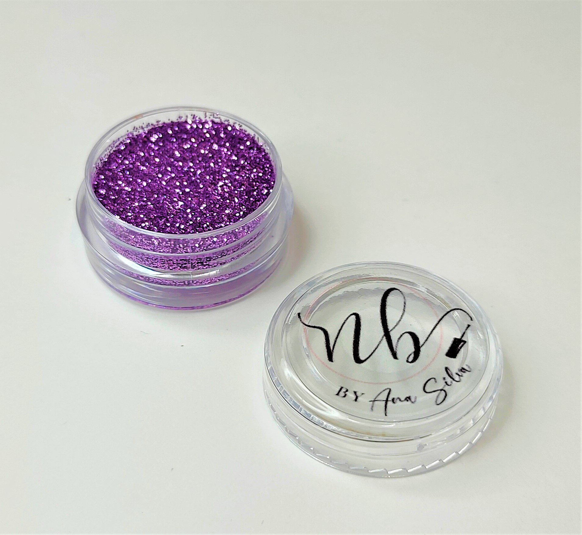 Pote transparente com purpurina roxa e tampa com inscrição NB BY Ana Silva
