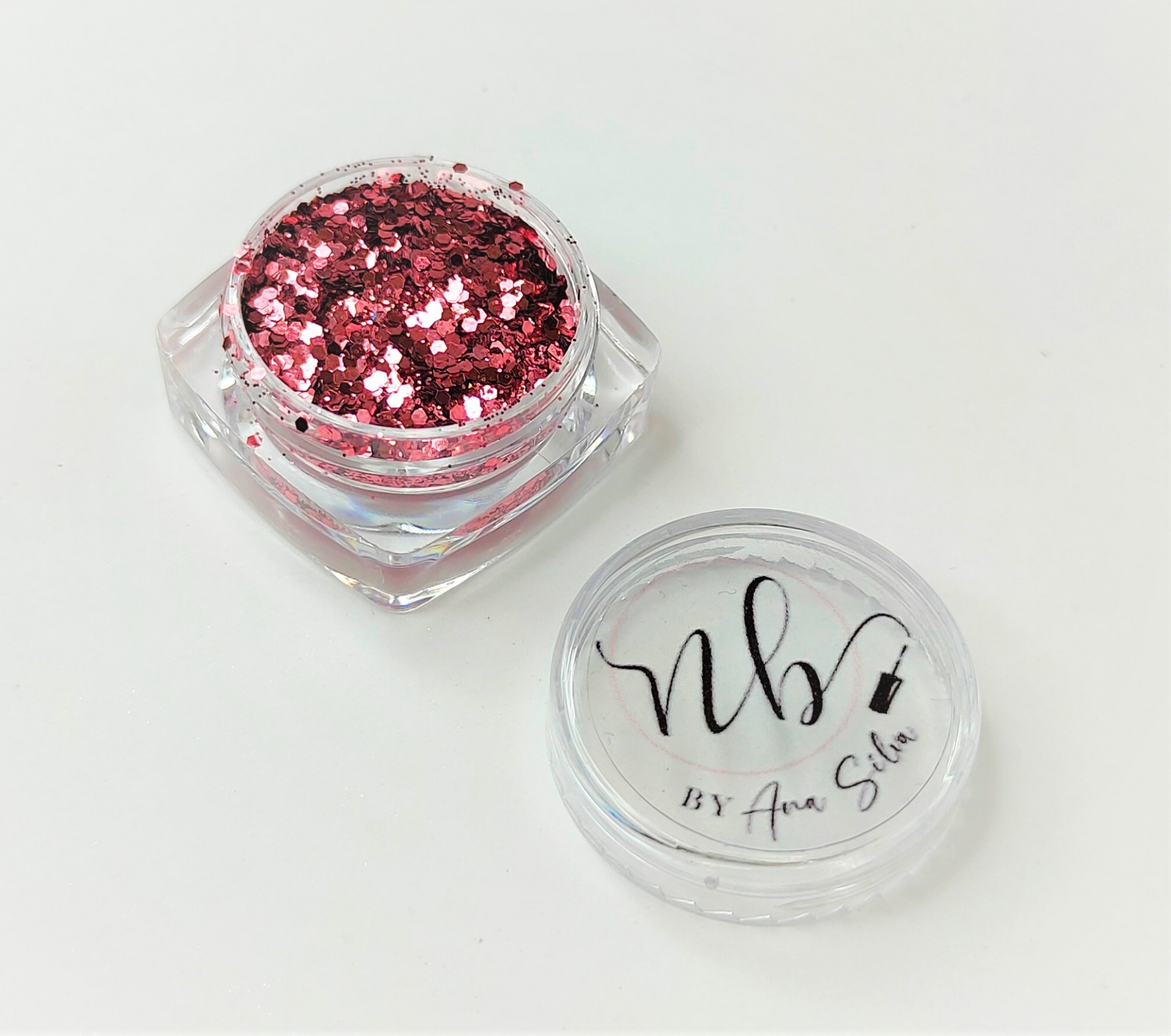 Frasco de glitter rosa metálico com tampa transparente e texto negro.