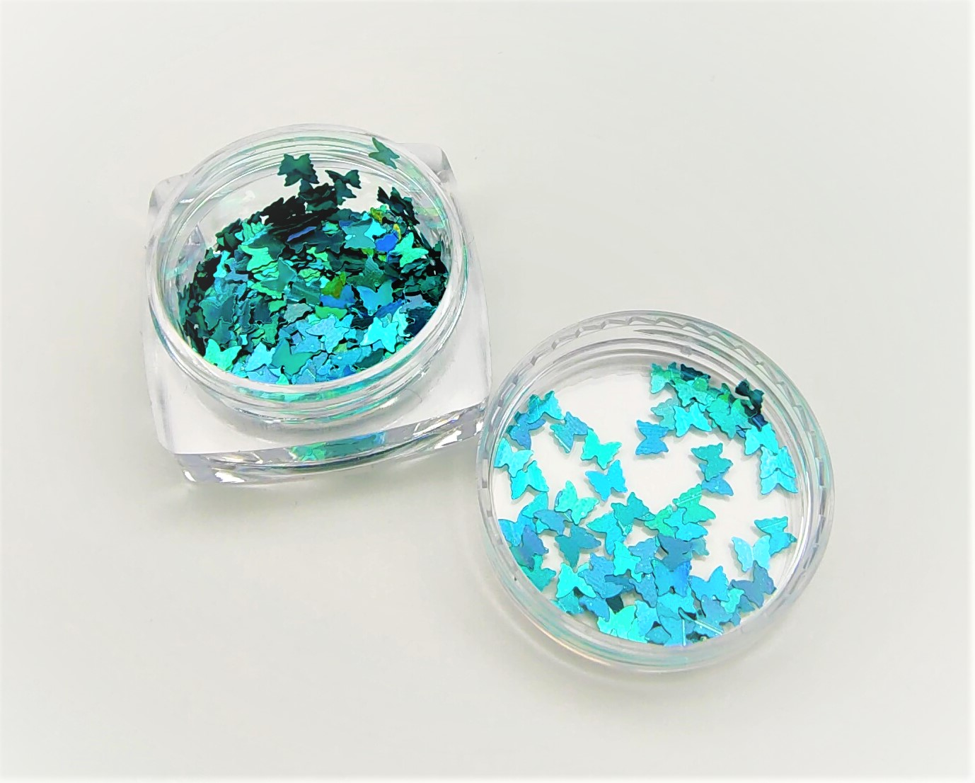 Frascos com lantejoulas de borboleta azuis e verdes