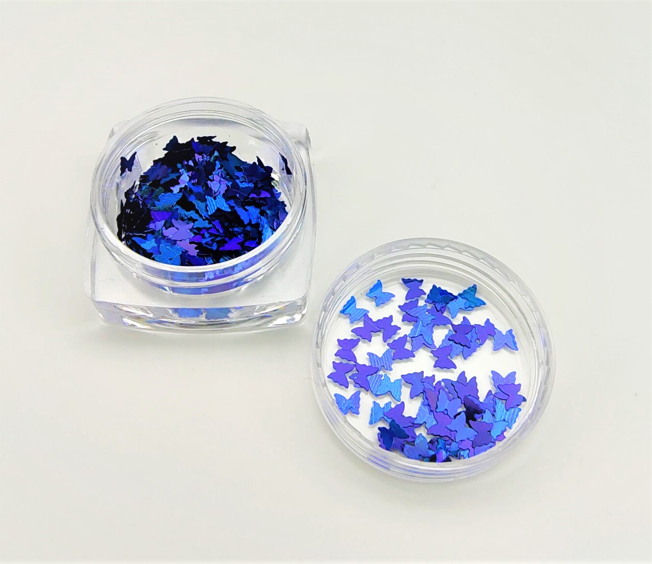 Caixas transparentes com pedaços brilhantes em forma de borboletas azul e roxo