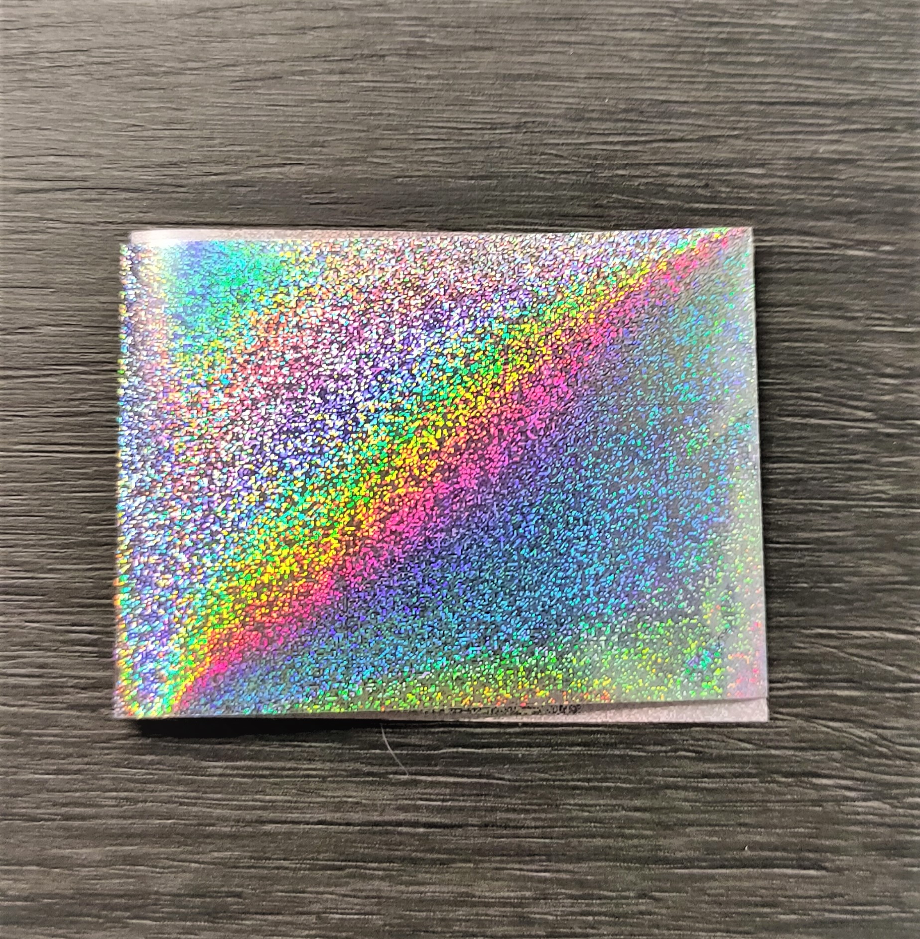Caixa pequena holográfica colorida sobre madeira escura