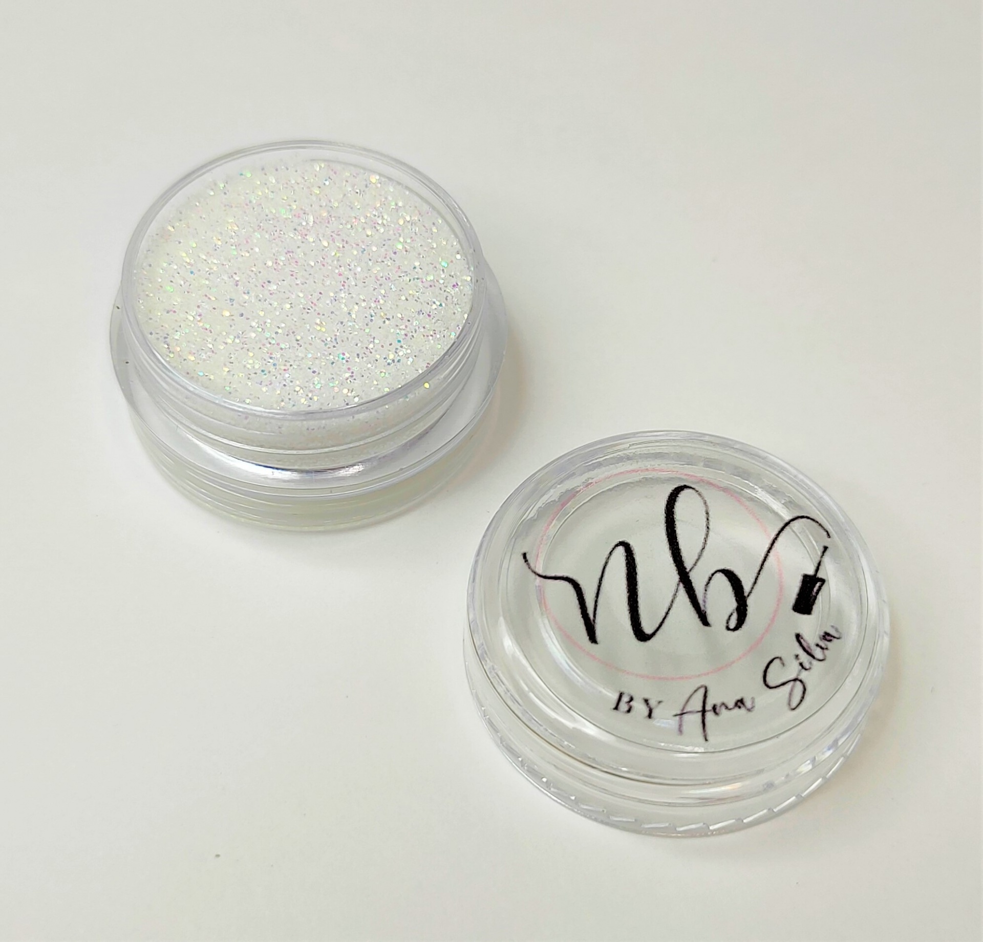 Pote pequeno com glitter branco e tampa com inscrição 'nb BY Ana Silva'