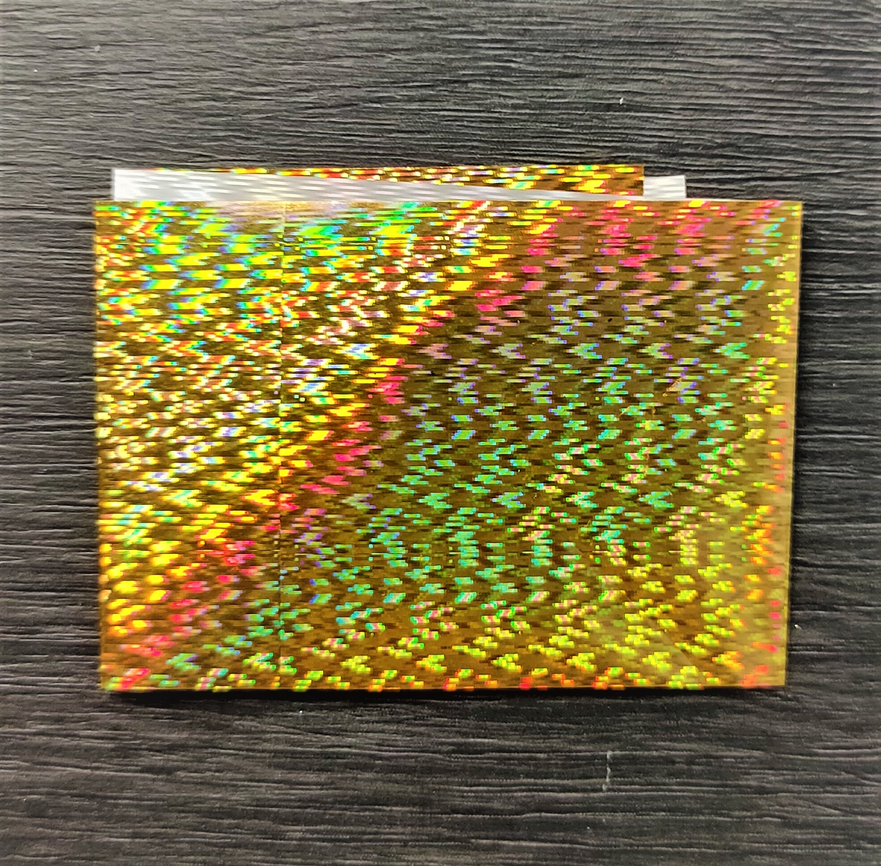 Papel holográfico dourado com padrão refletivo multicolorido
