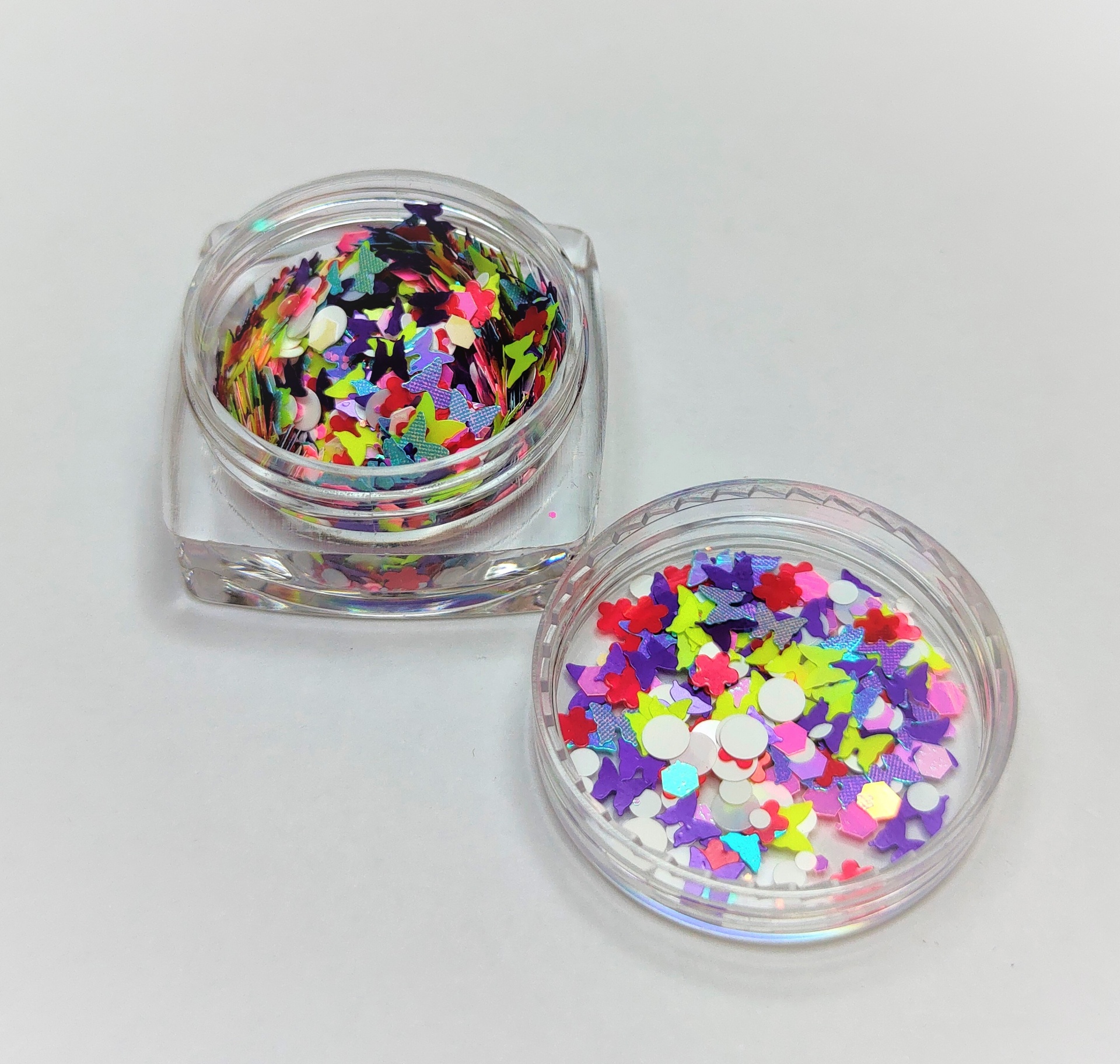 Recipientes de confetes coloridos com formas variadas sobre fundo branco