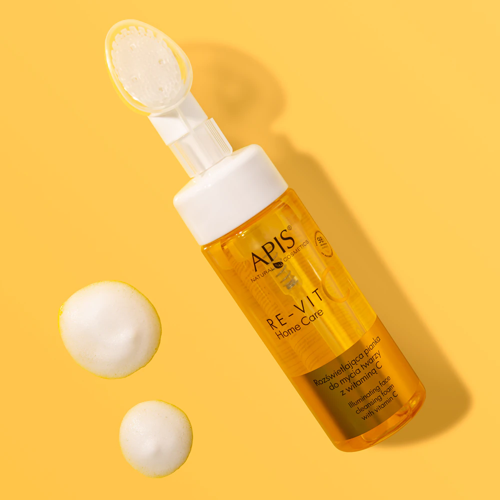 Frasco amarelo de produto cosmético APIS Re-Vit Home Care com creme ao lado sobre fundo amarelo
