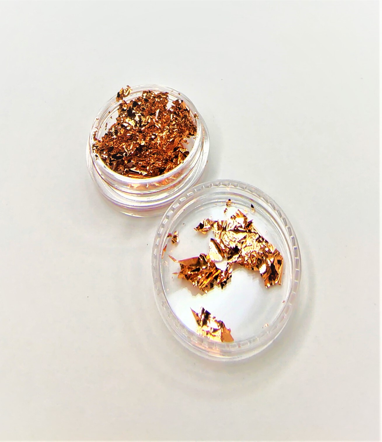 Contêiner transparente com flocos metálicos dourados em superfície branca