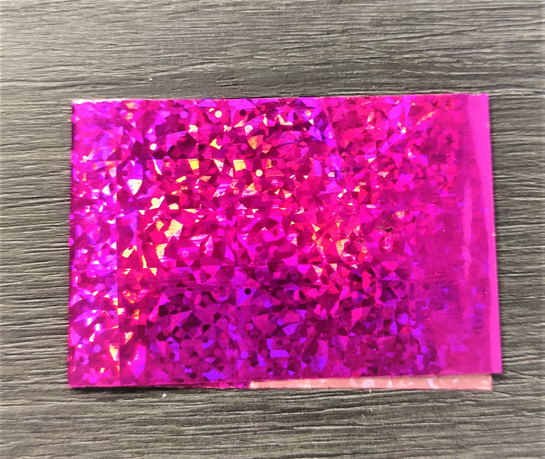 Cartão holográfico rosa sobre mesa de madeira