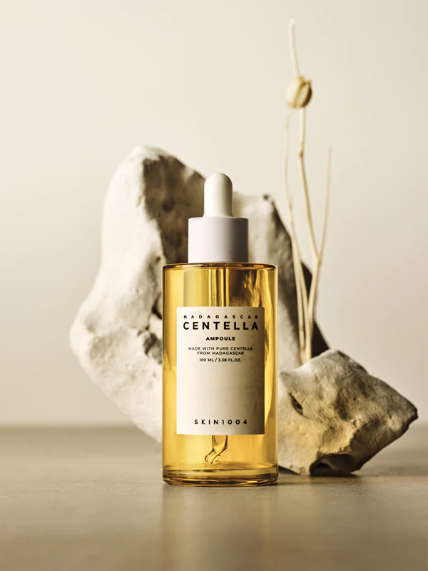 frasco de sérum amarelo com conta-gotas branco e rótulo branco em fundo com pedras