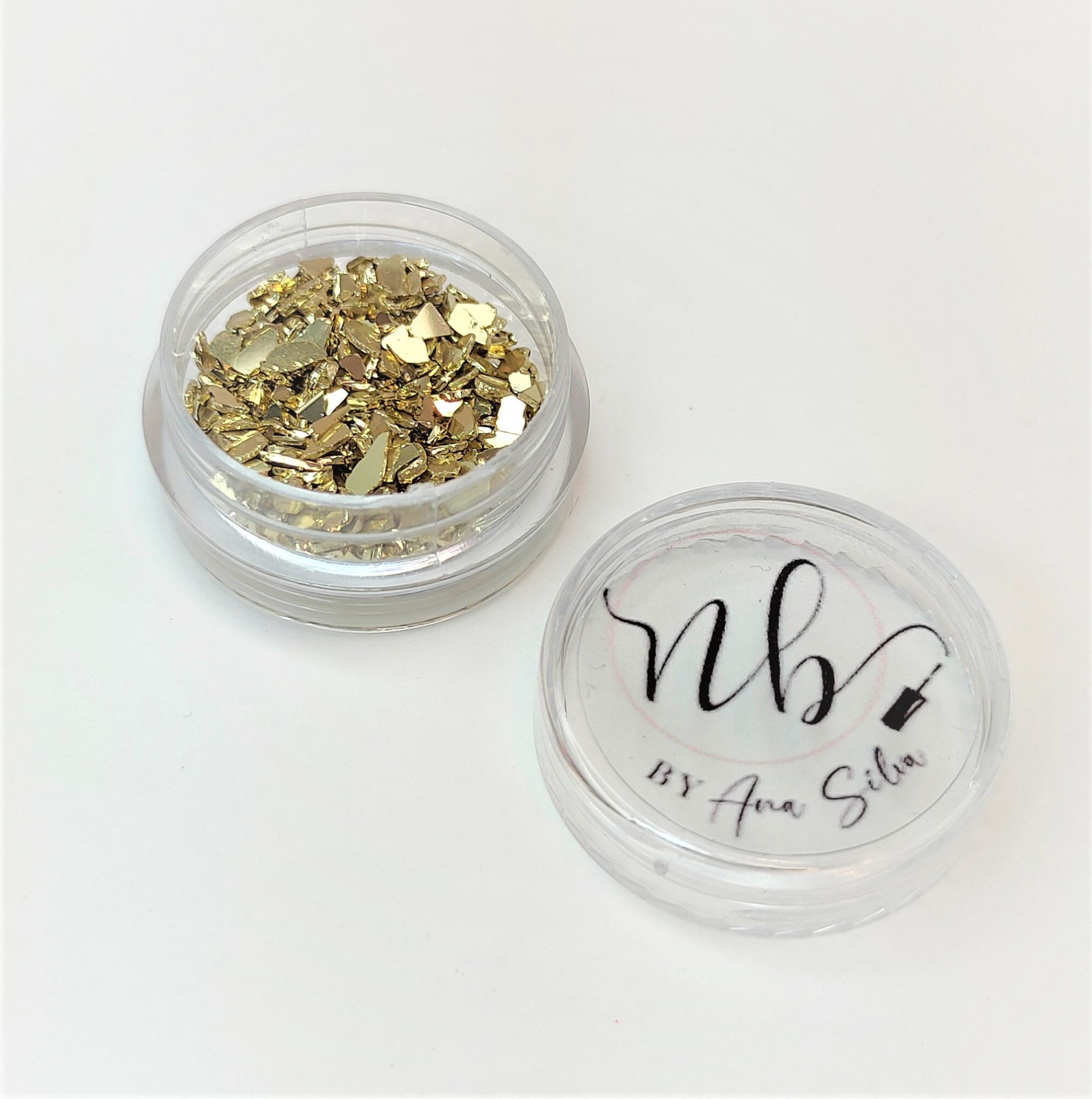 Frasco transparente com flocos dourados e tampa com texto 'nb BY Ana Silva'