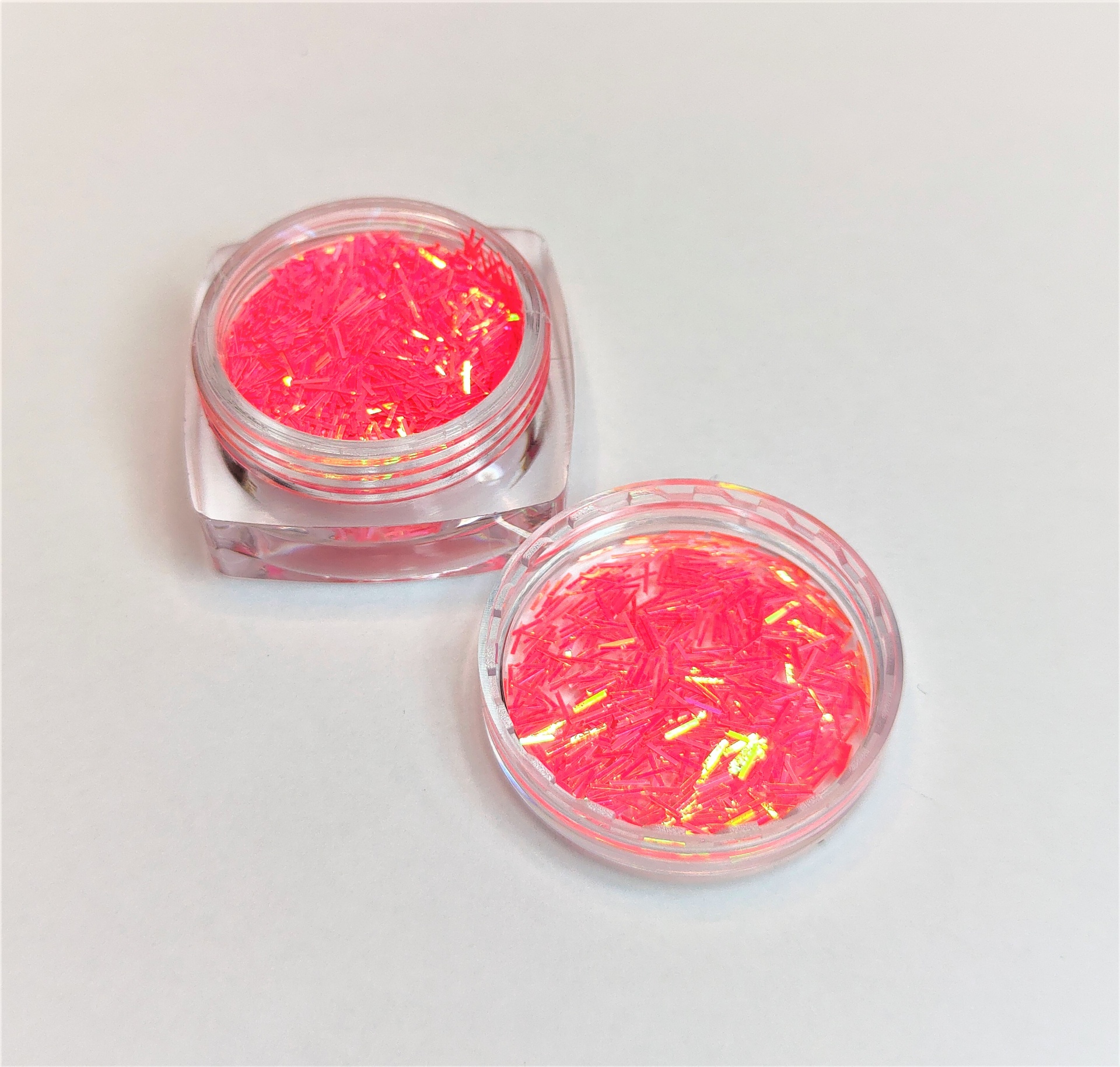 Frascos pequenos contendo glitter cor de rosa com reflexos dourados