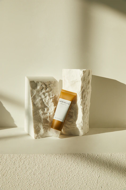 Frasco âmbar de gel com rótulo branco entre duas pedras brancas