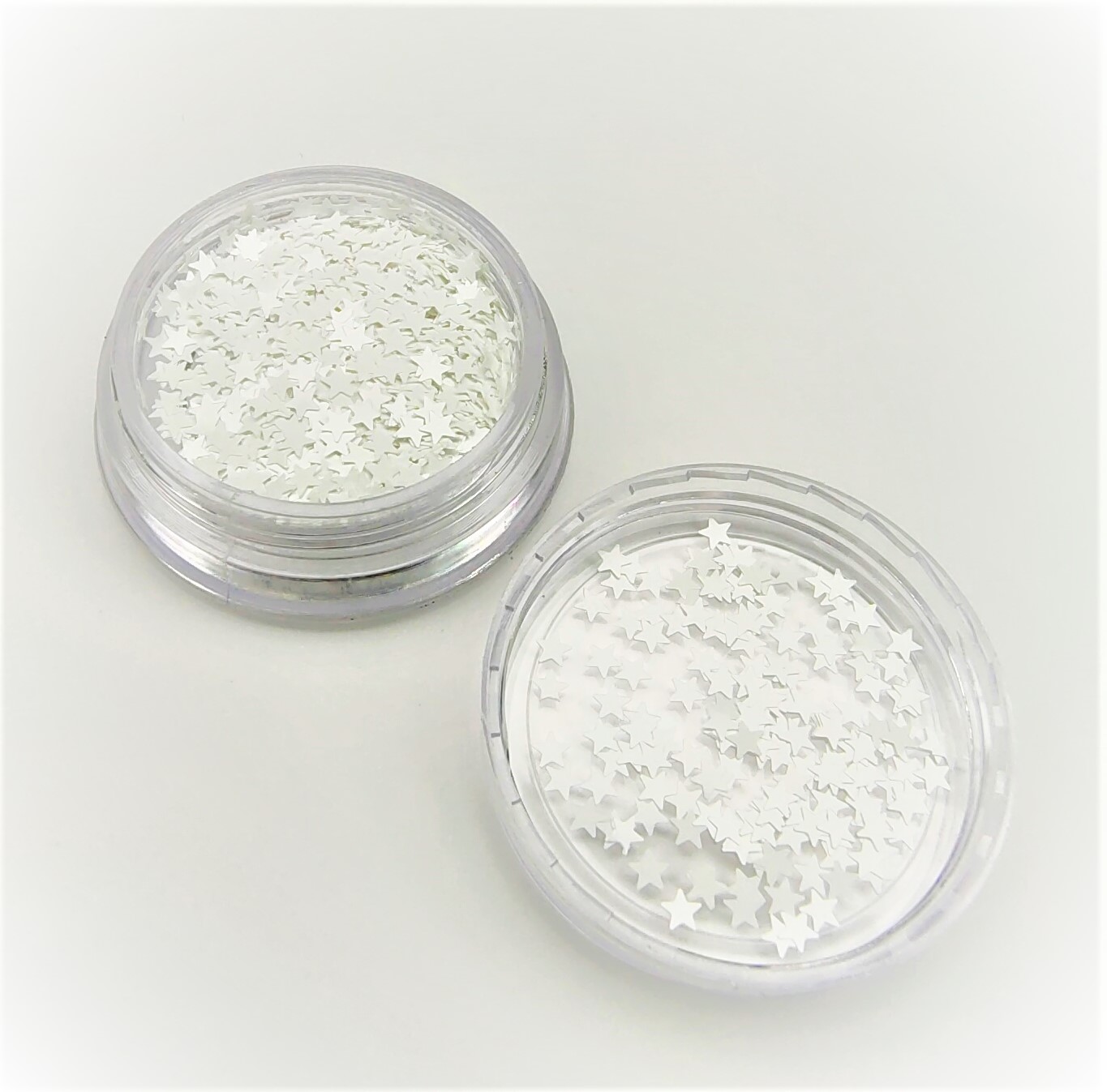 Duas caixas transparentes com glitter branco em forma de estrelas