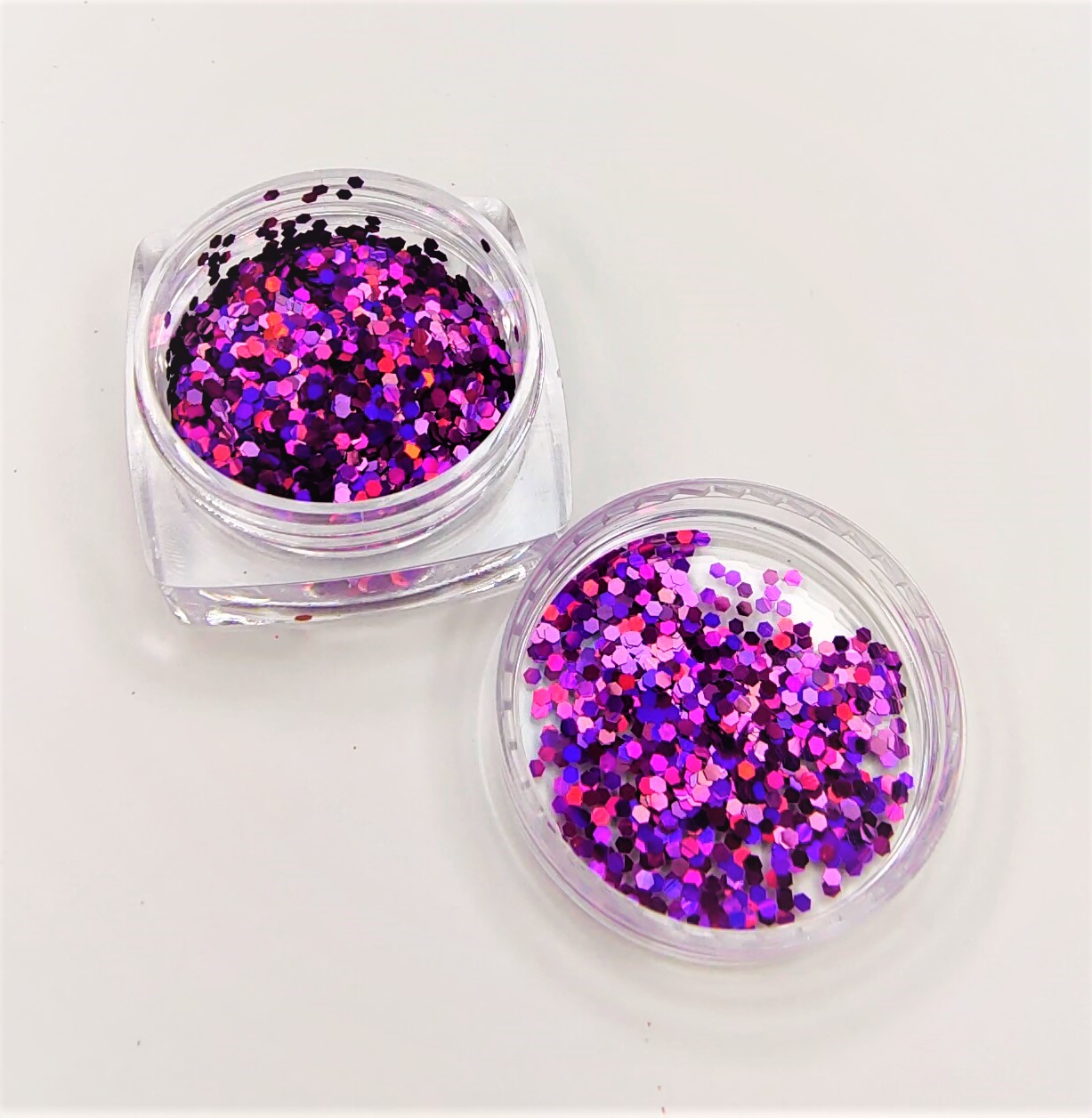 Dois recipientes transparentes com glitter colorido em tons de rosa e roxo
