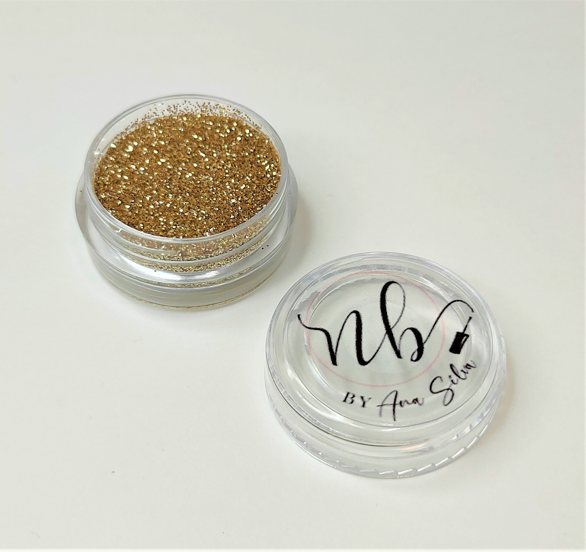 Pote pequeno transparente com purpurina dourada e tampa com texto e desenho pretos