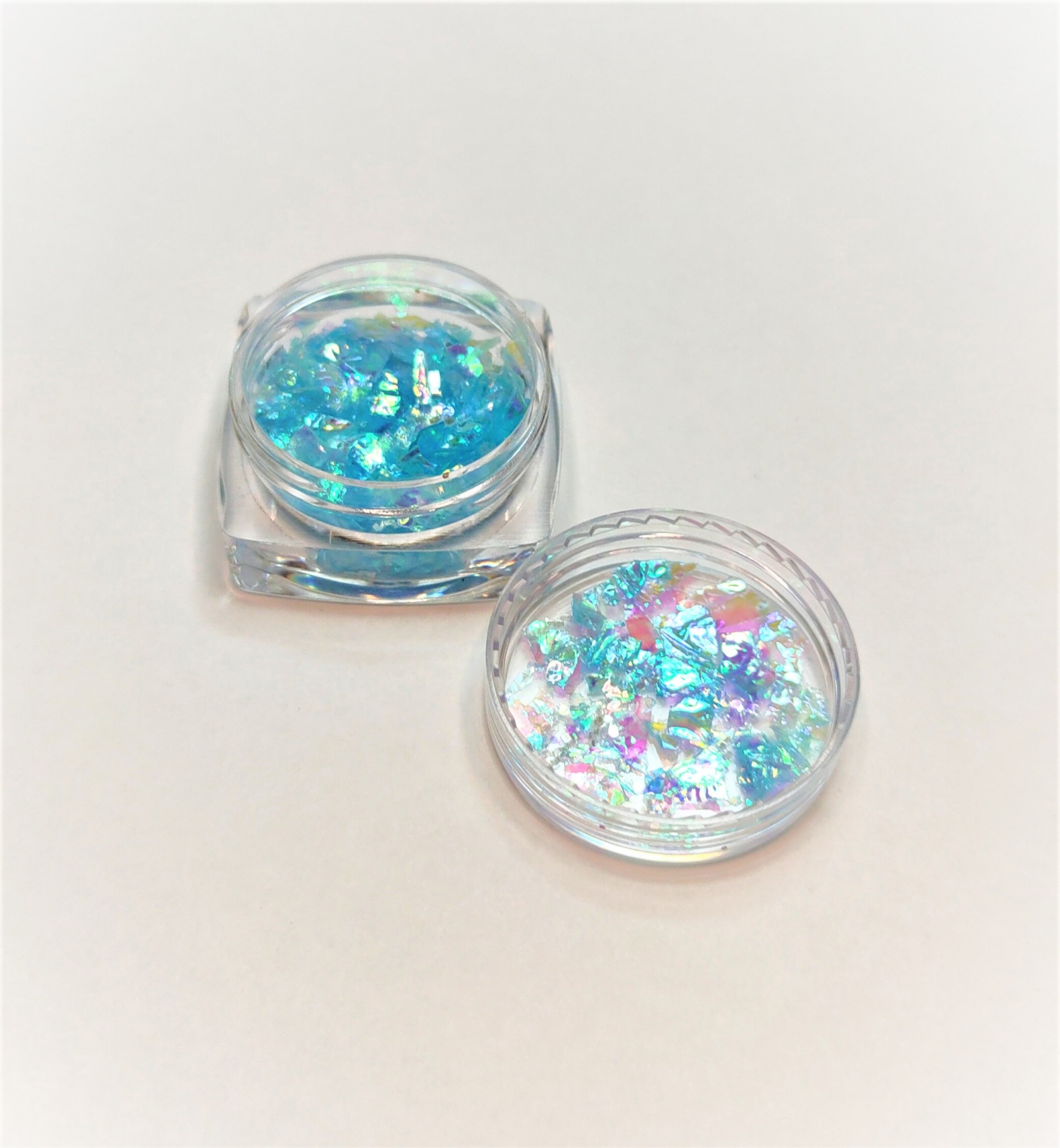 Frascos pequenos com pedaços brilhantes iridescentes coloridos