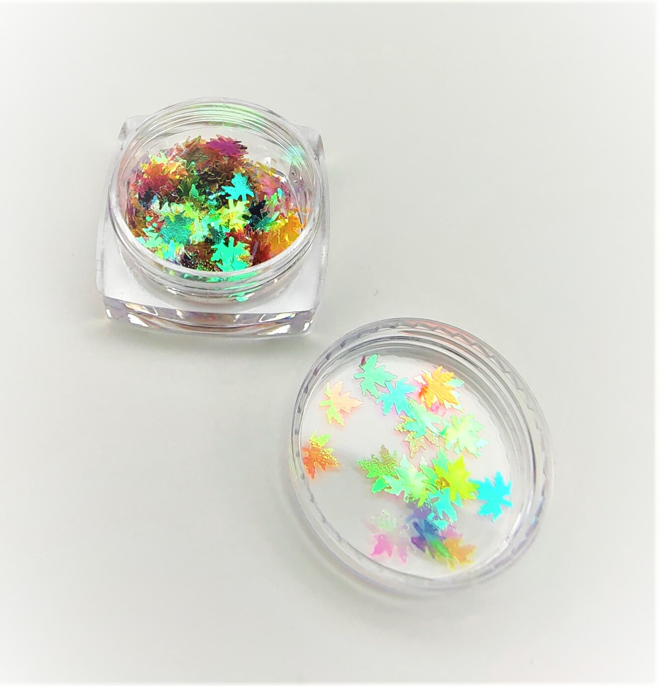 Frascos transparentes com confetes holográficos de folhas coloridas