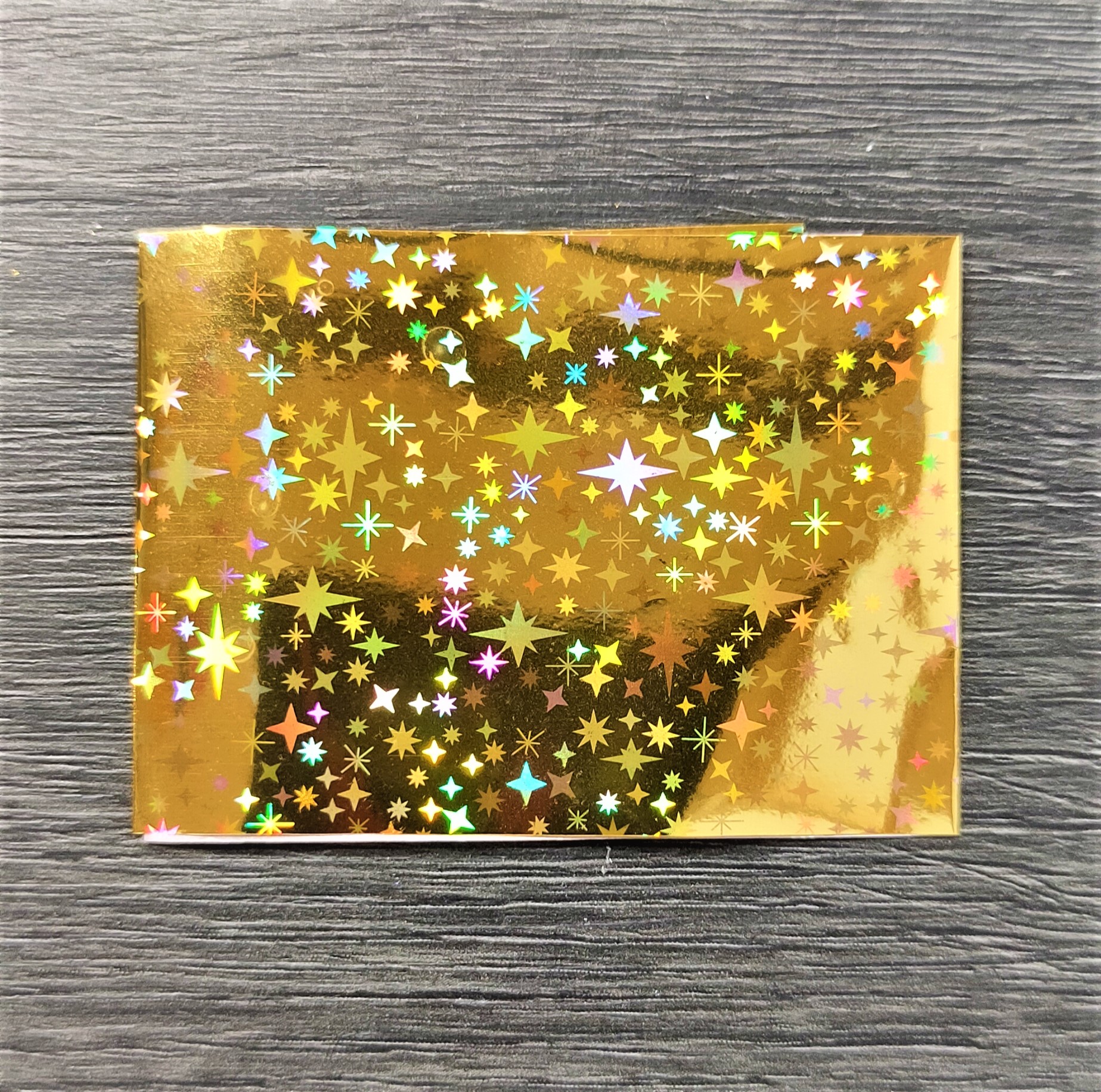 Envelope dourado holográfico com estrelas multicoloridas