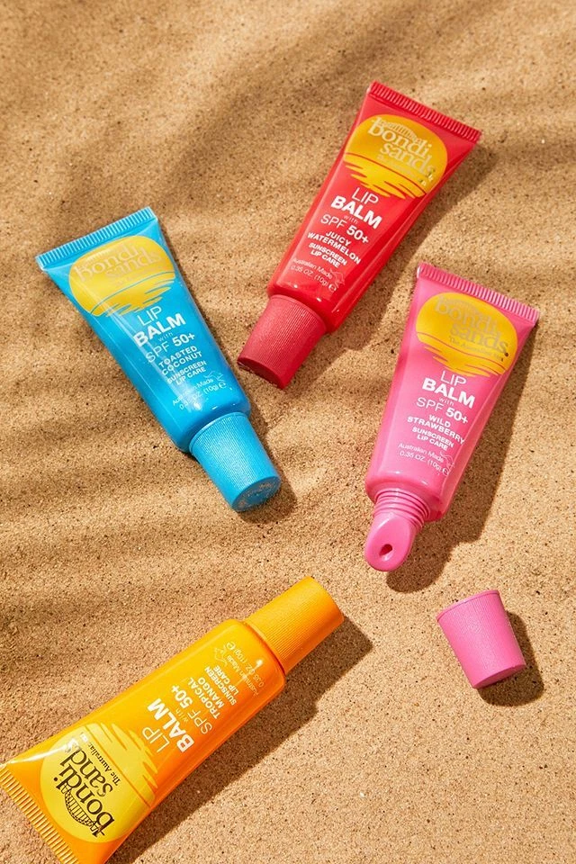 Tubos coloridos de protetor labial Bondi Sands na areia