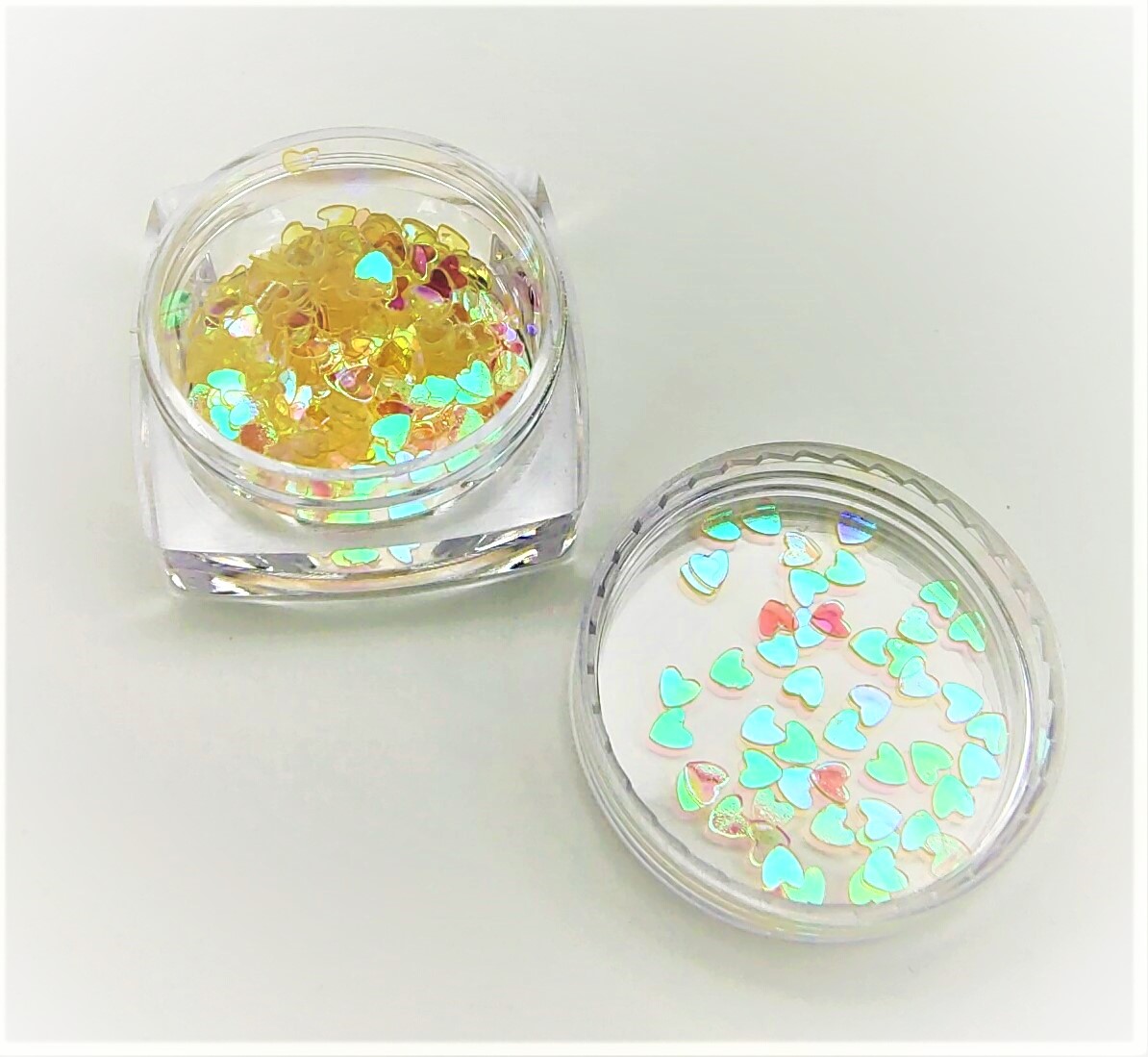 Caixas transparentes com partículas brilhantes em forma de corações