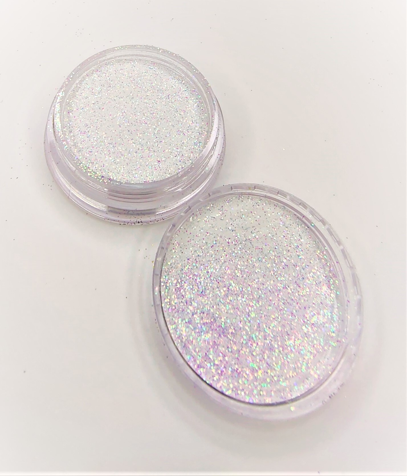 Dois recipientes de glitter holográfico em fundo branco