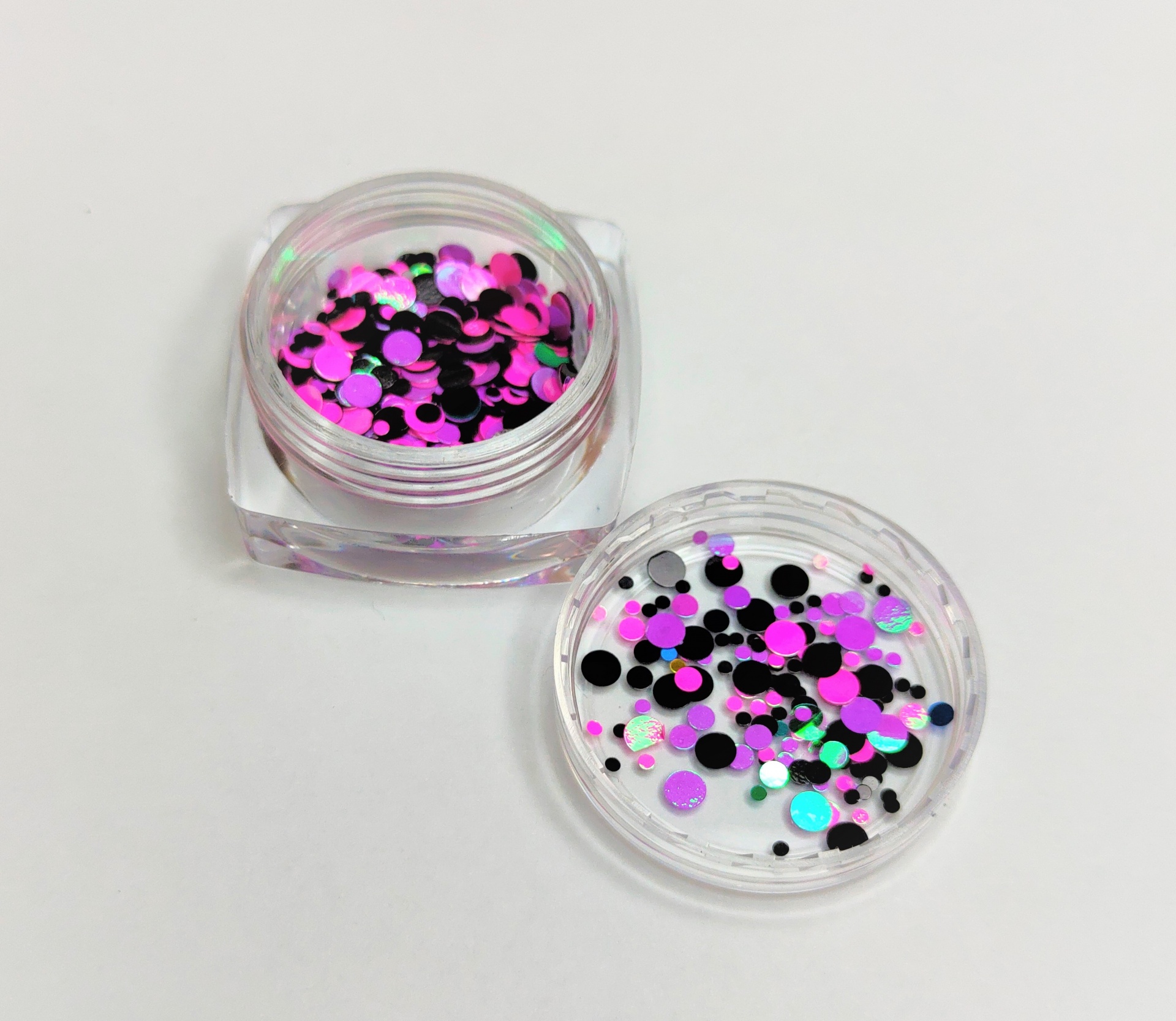 Frasco com glitter colorido rosa, preto e verde fluorescente e tampa aberta