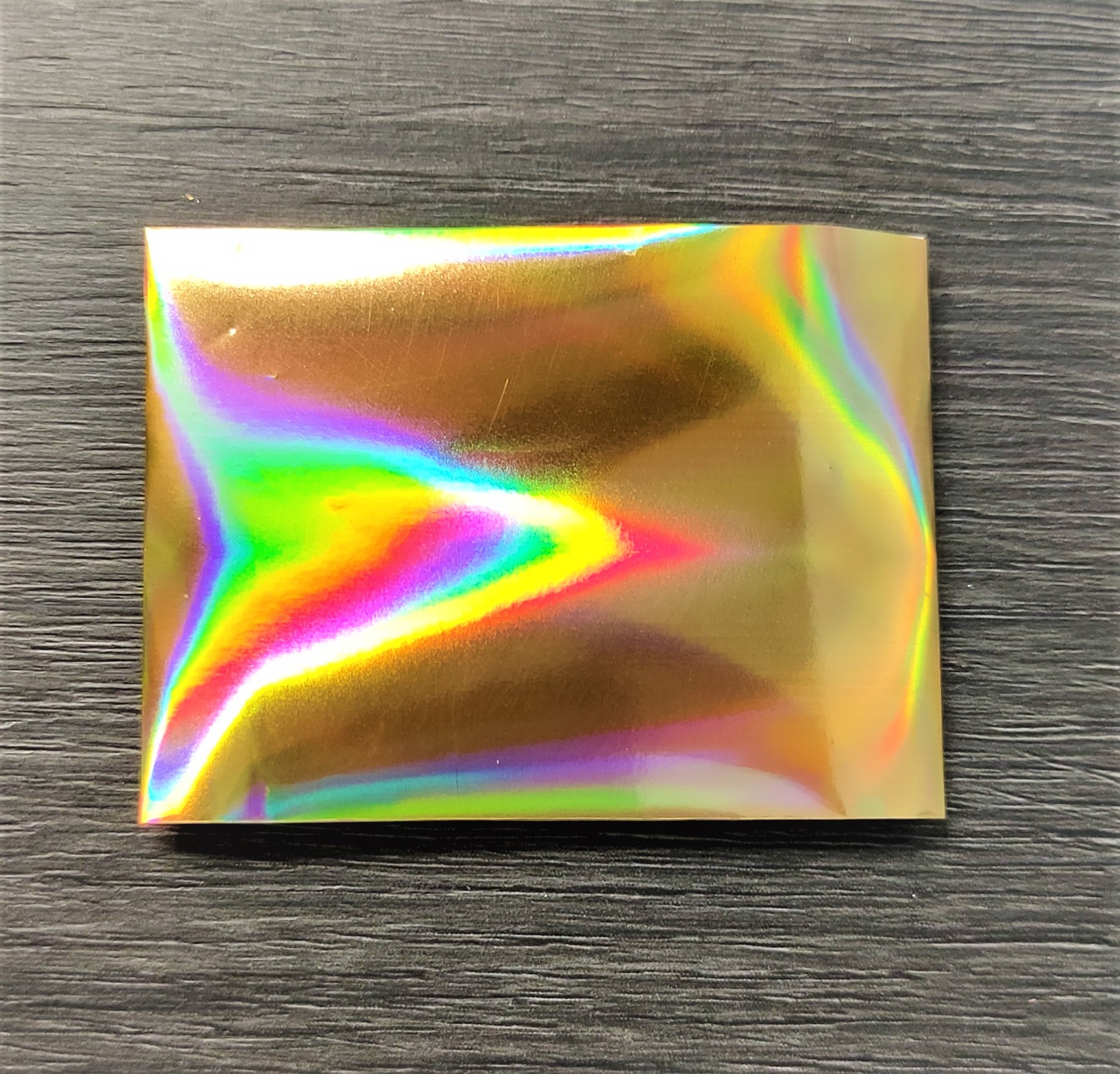 Pacote metálico iridescente sobre superfície de madeira escura