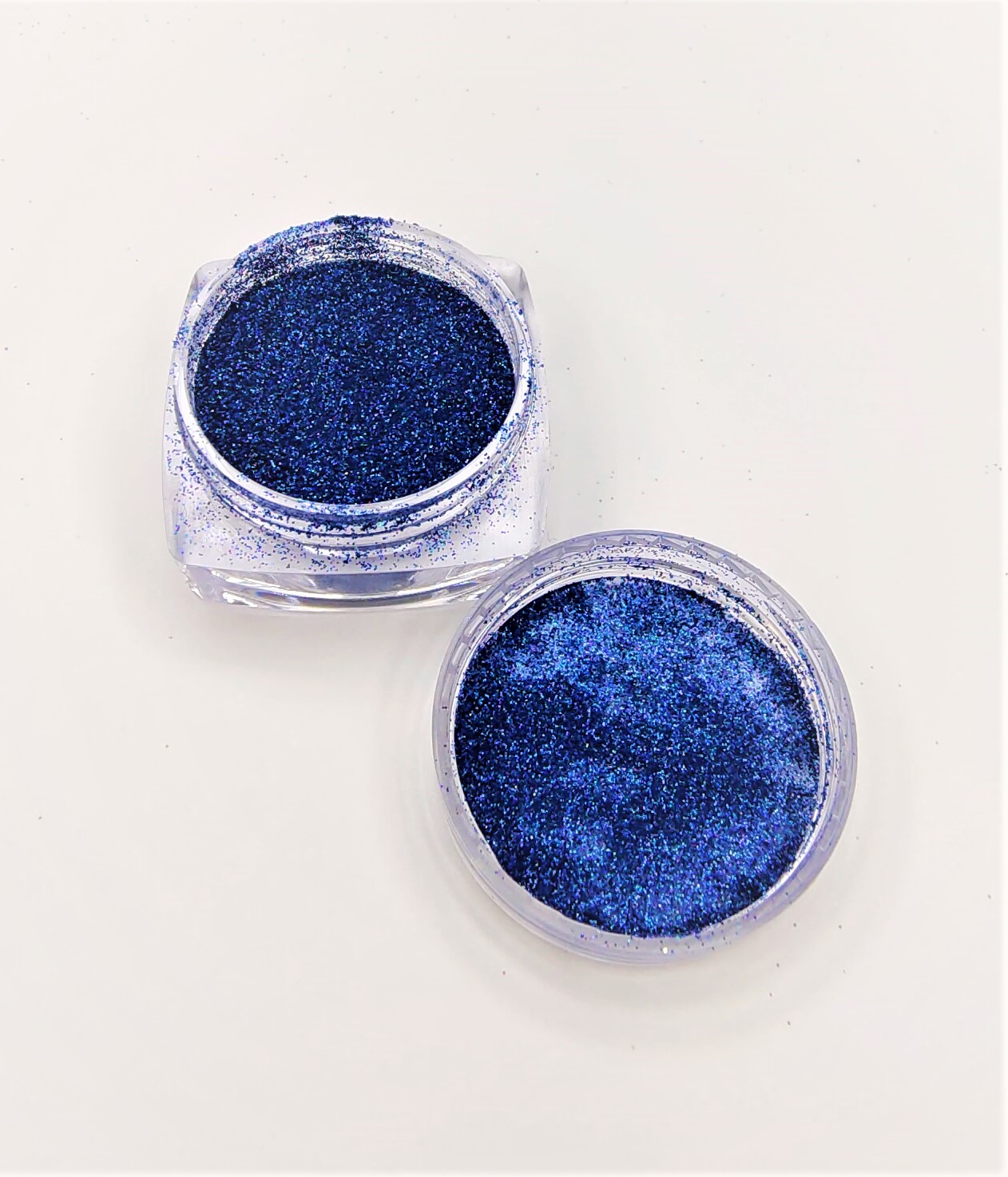 Dois pequenos frascos transparentes com glitter azul escuro brilhante
