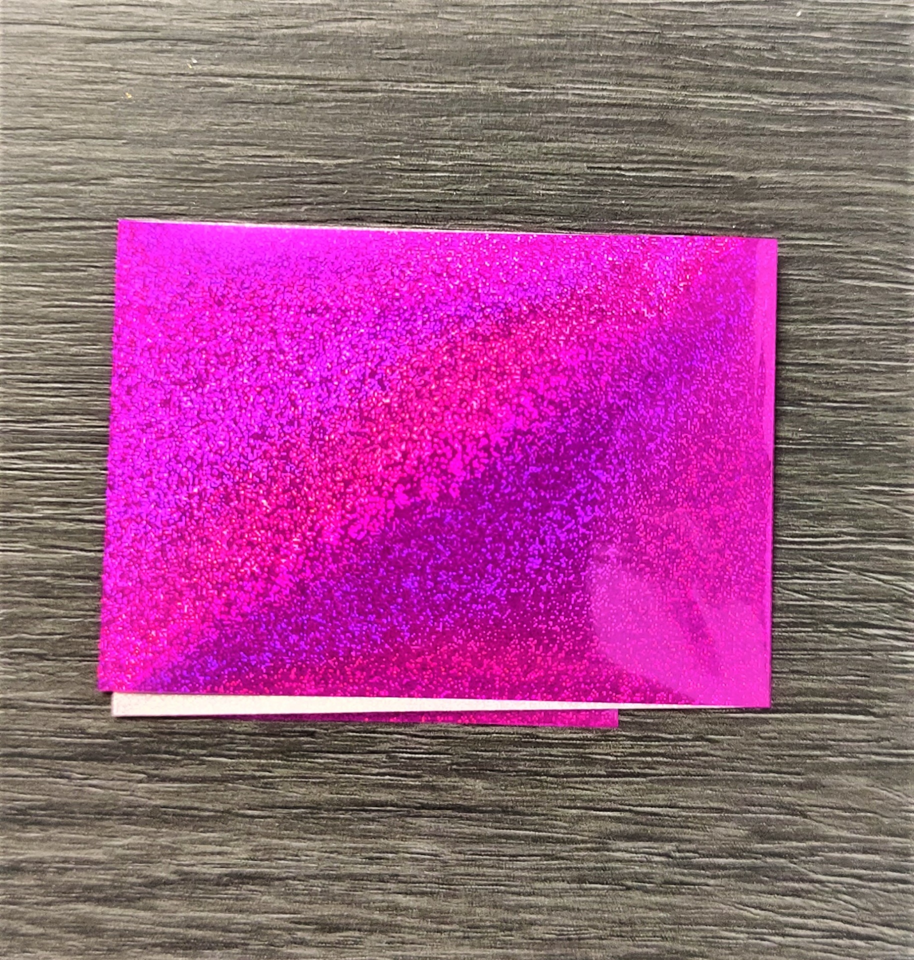 Pedaço de papel rosa fluorescente brilhante sobre superfície de madeira escura