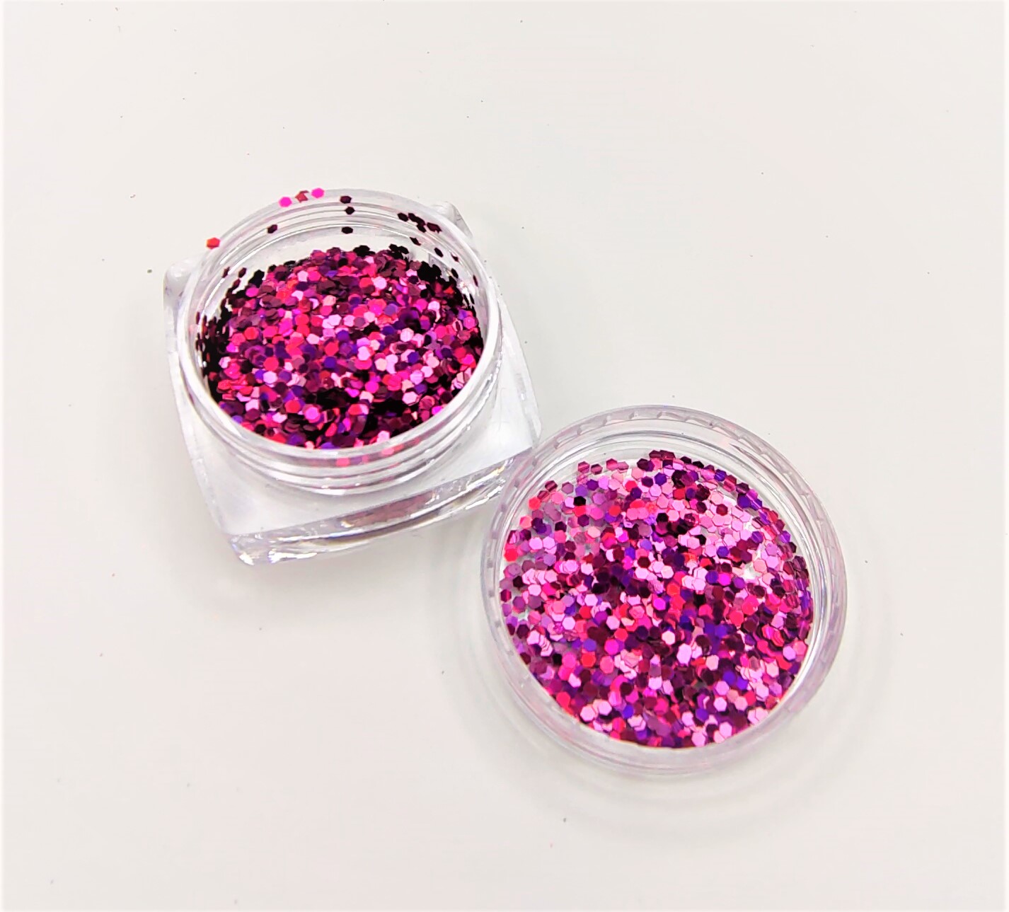 Dois frascos pequenos de glitter colorido em tons rosa e lilás